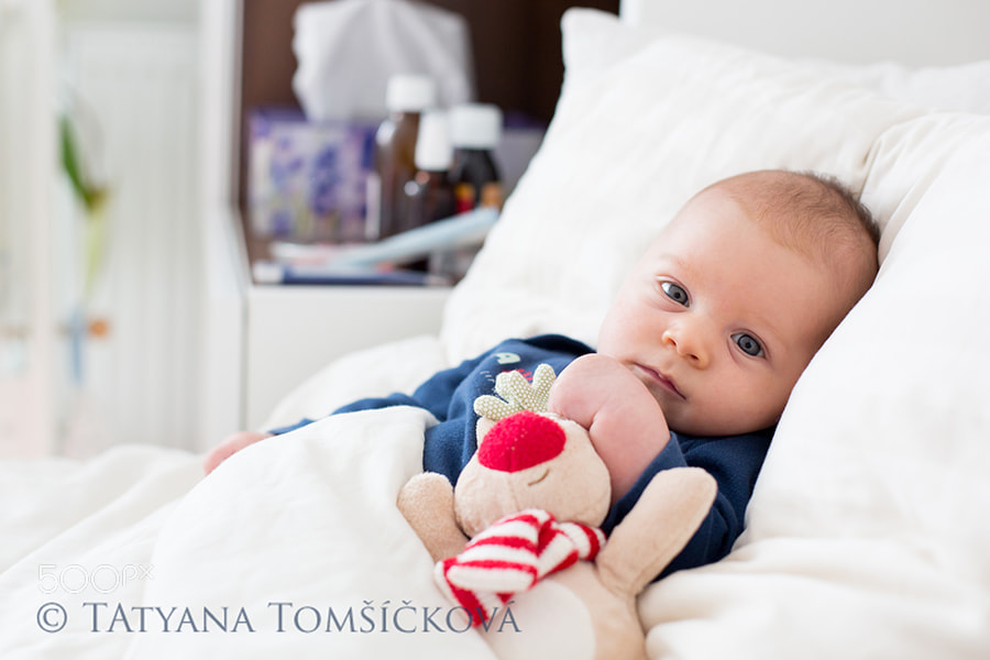 Cute newborn baby boy, lying in bed with cold