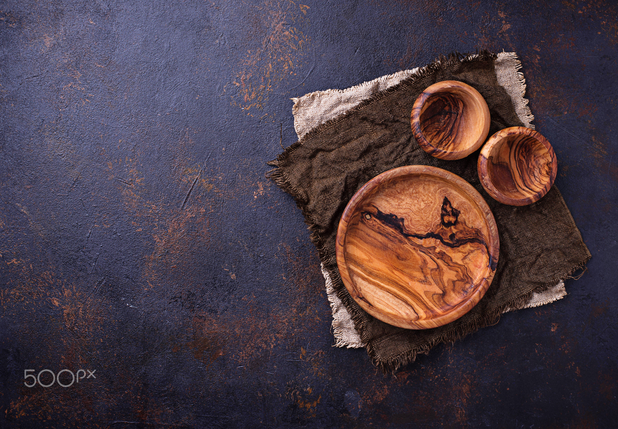 Empty wooden plate and bowls on rusty background