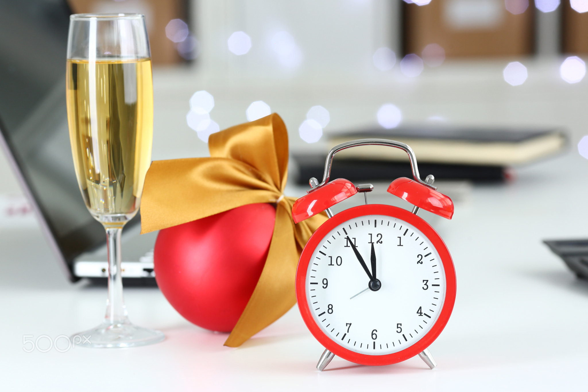 Red alarm clock and champagne goblet at office table