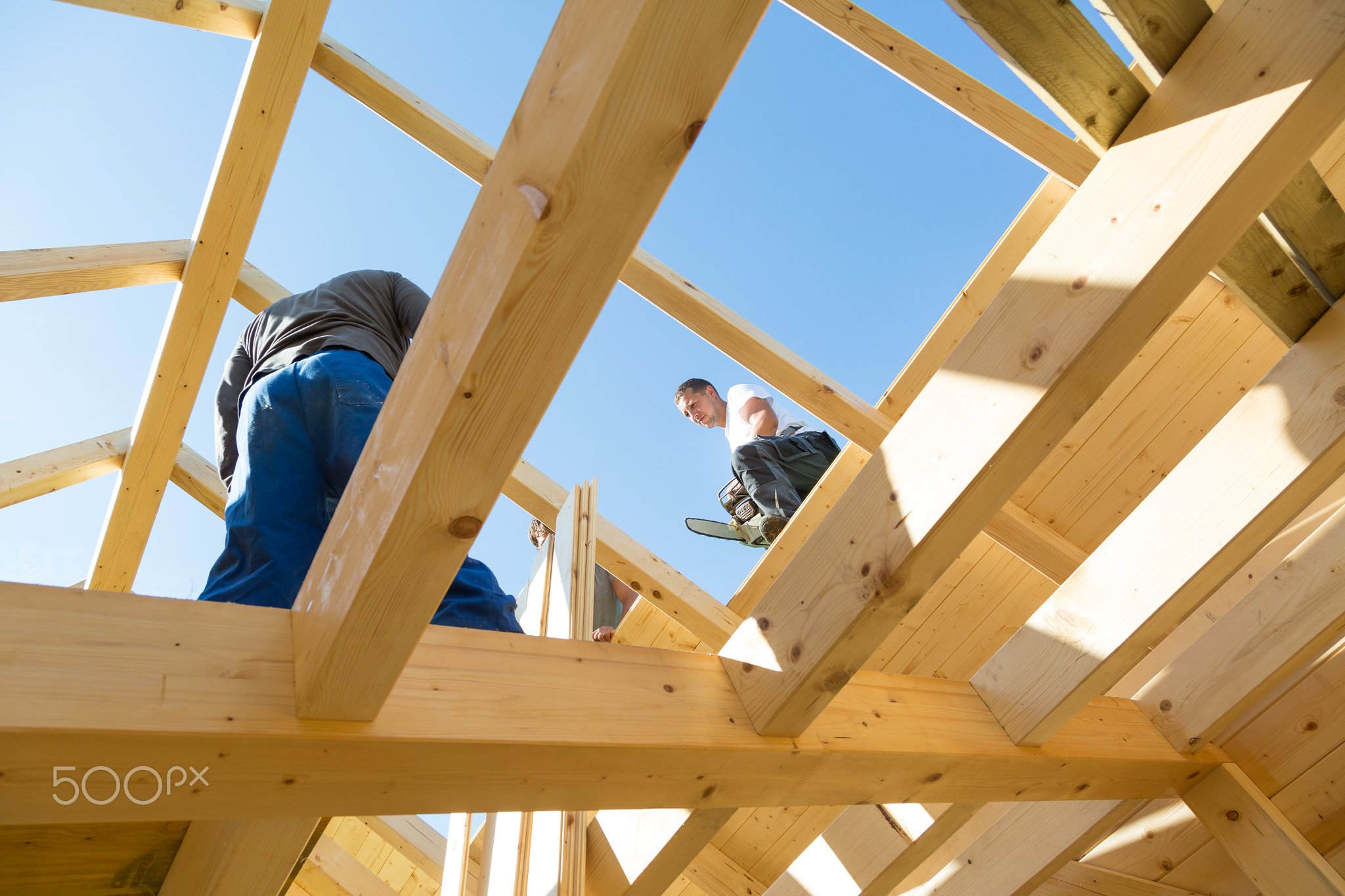 Builders at work with wooden roof construction.