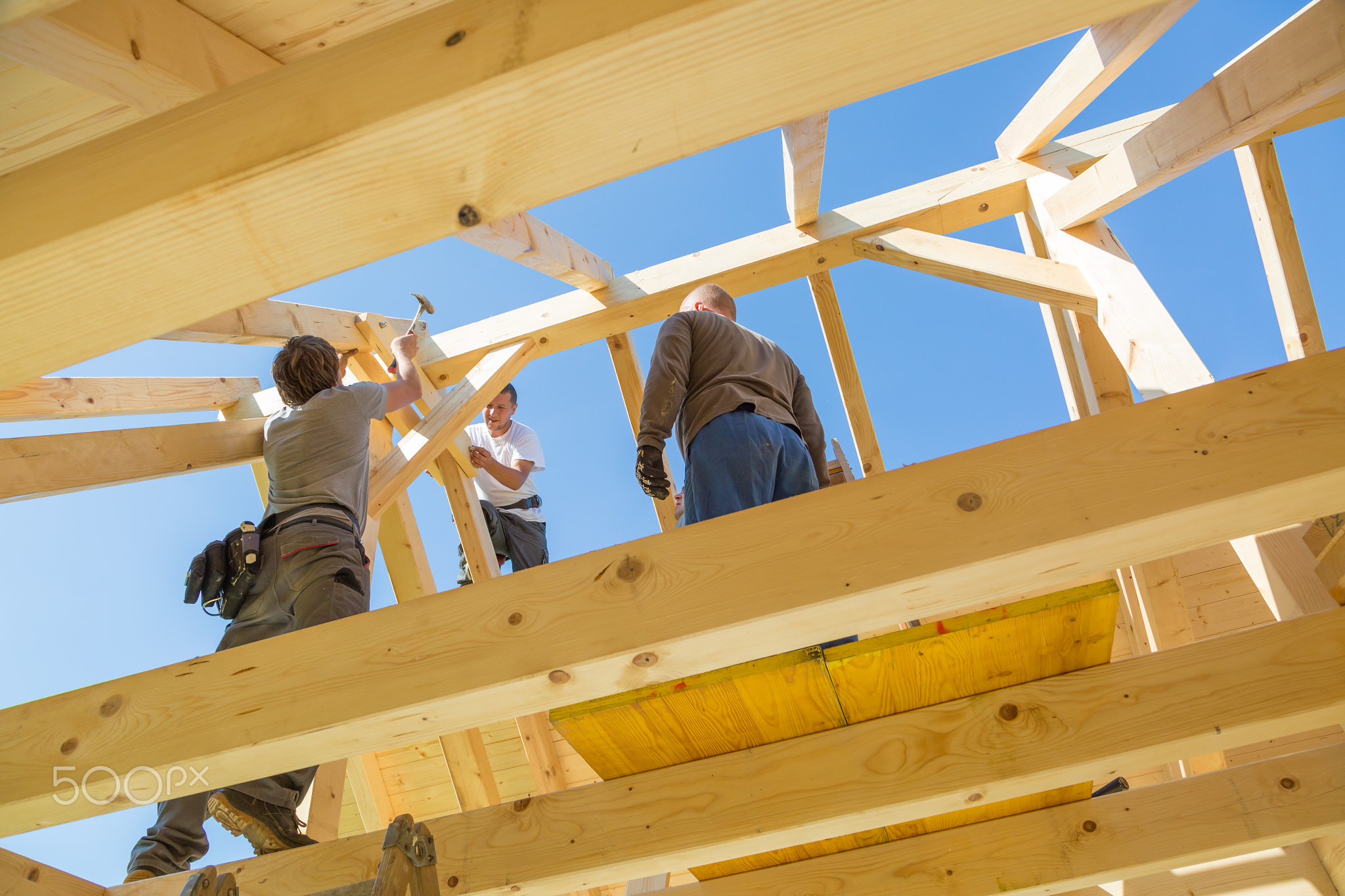 Builders at work with wooden roof construction.