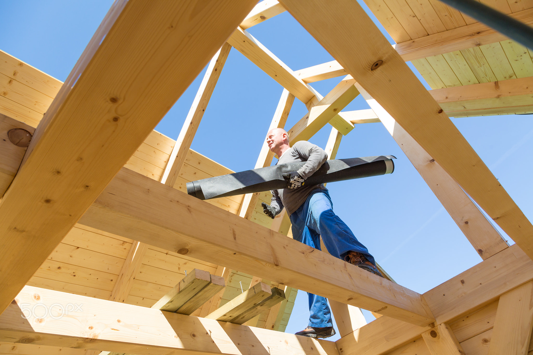 Builder at work with wooden roof construction.