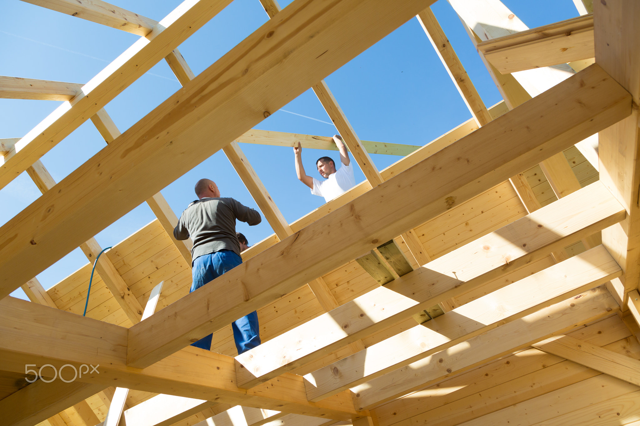 Builders at work with wooden roof construction.