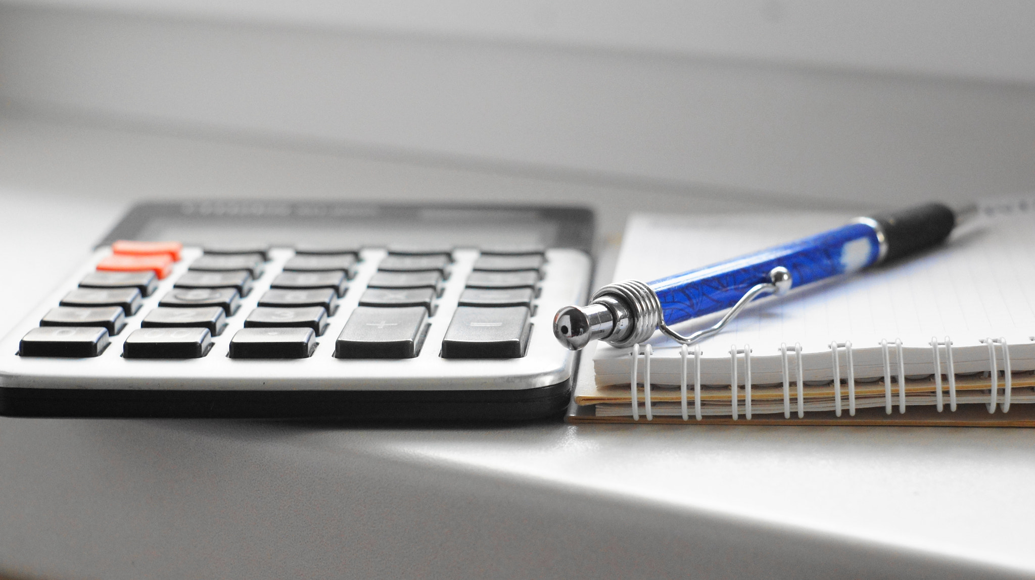 Calculator, pen and paper notepad