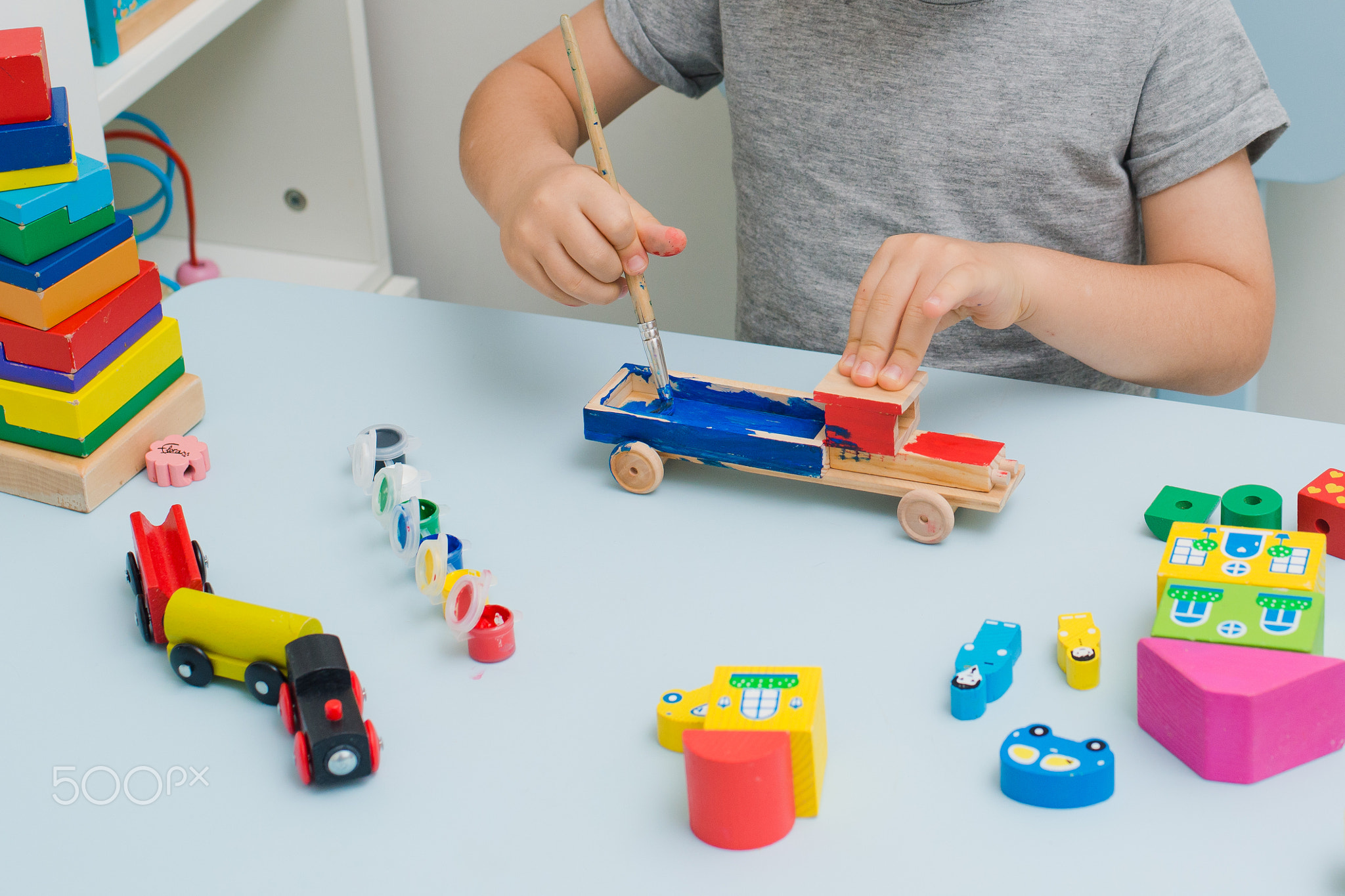 Hands of a child paint a wooden machine