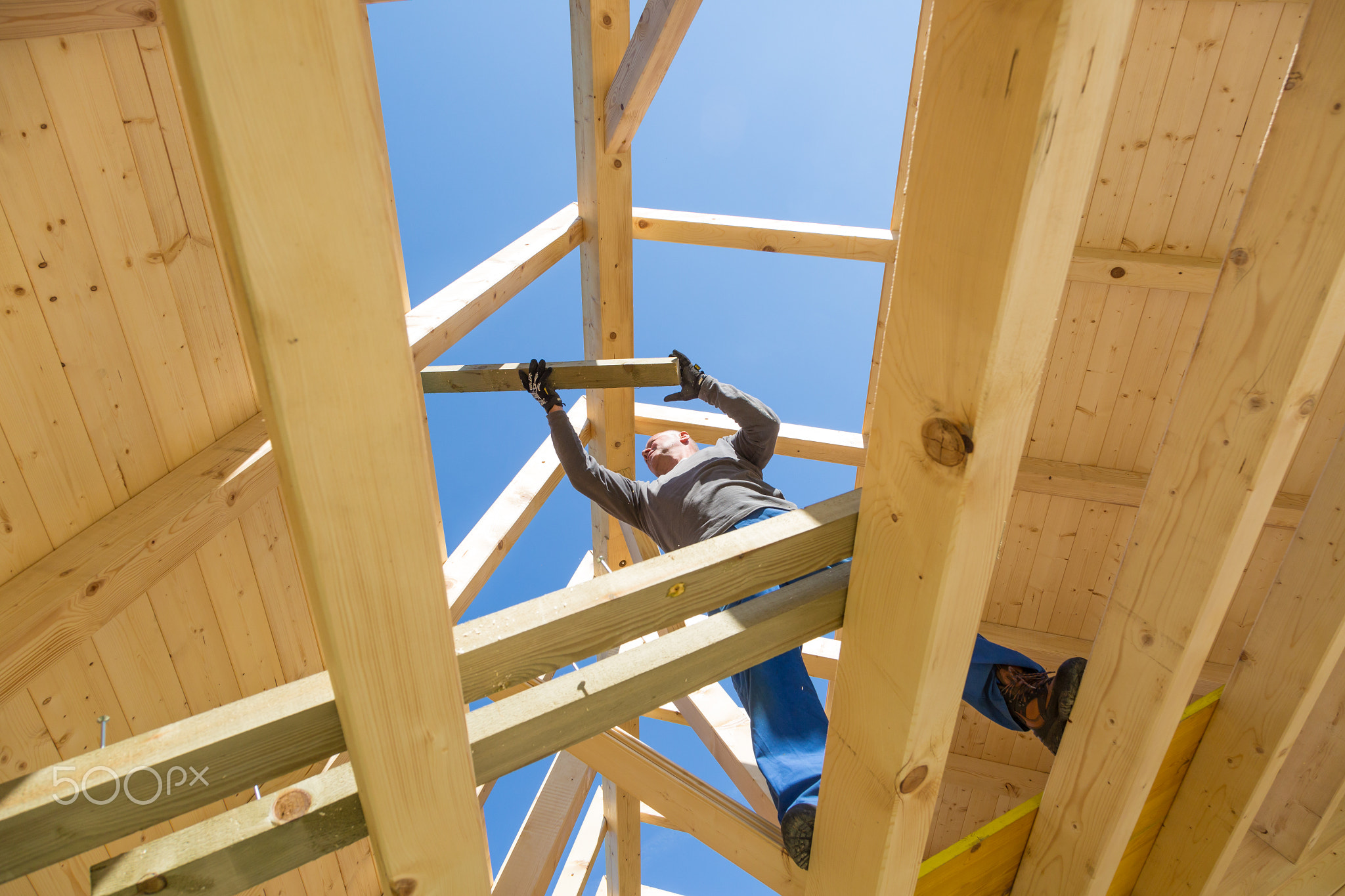 Builder at work with wooden roof construction.