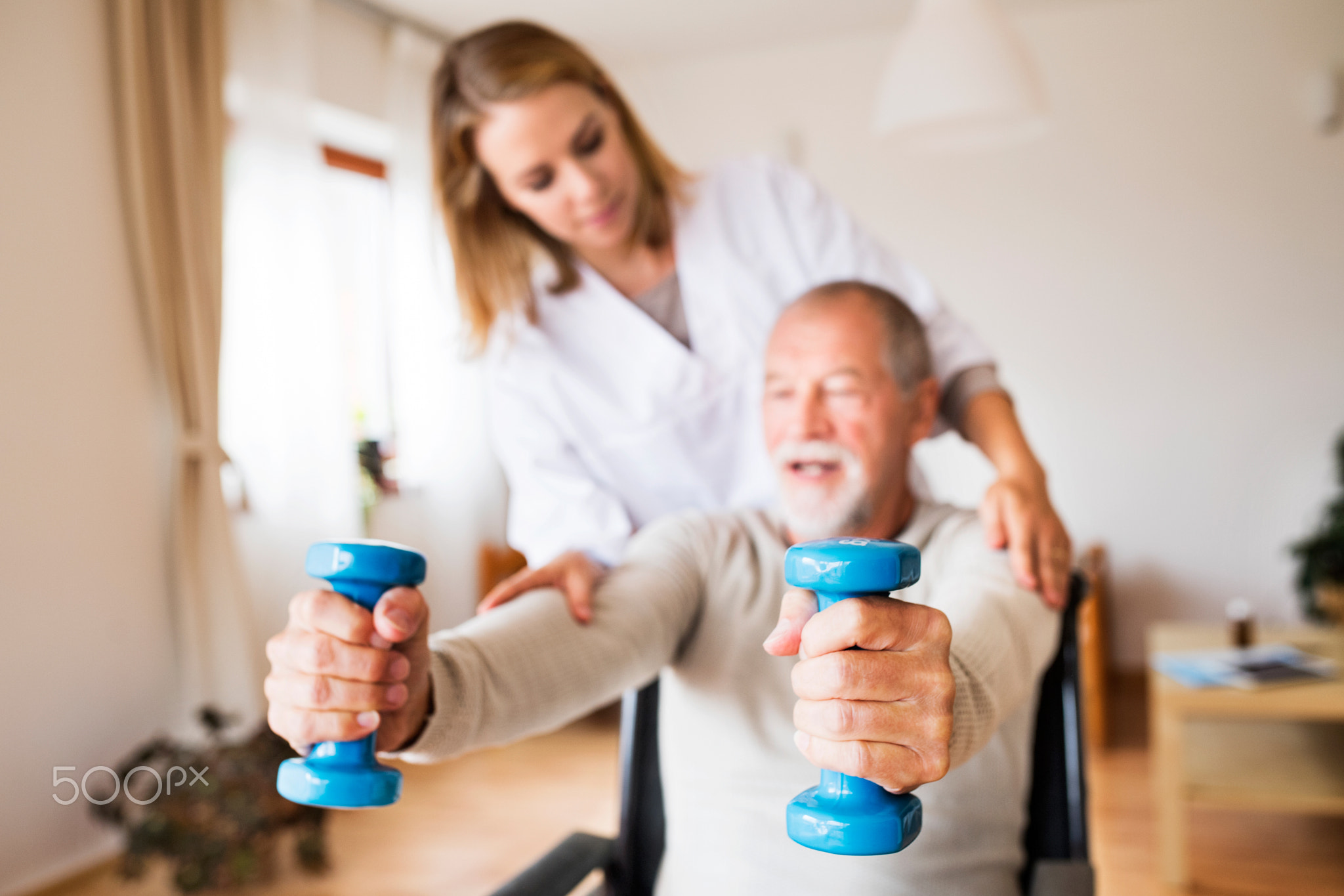 Nurse and senior man in wheelchair during home visit.