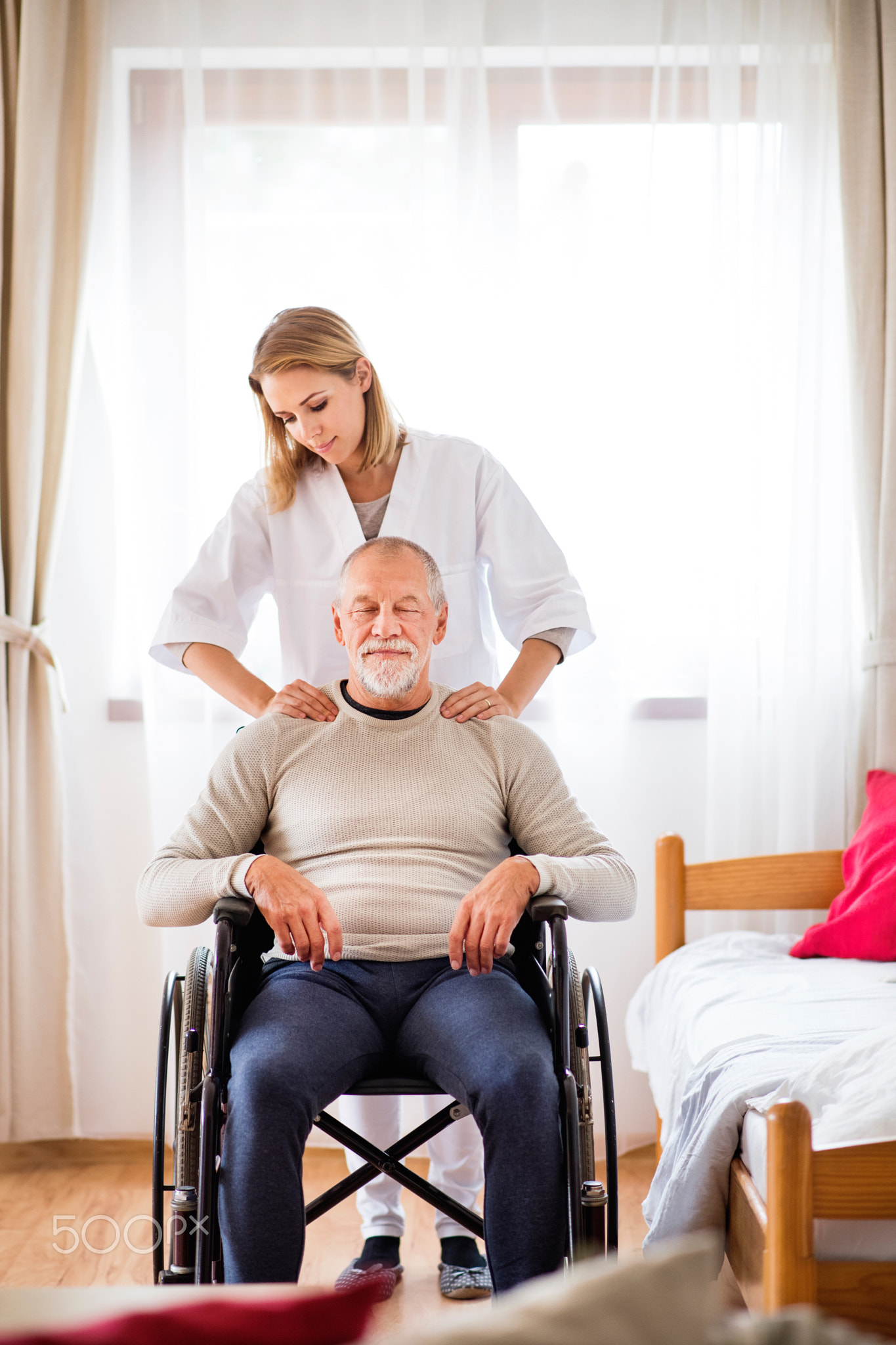 Nurse and senior man in wheelchair during home visit.