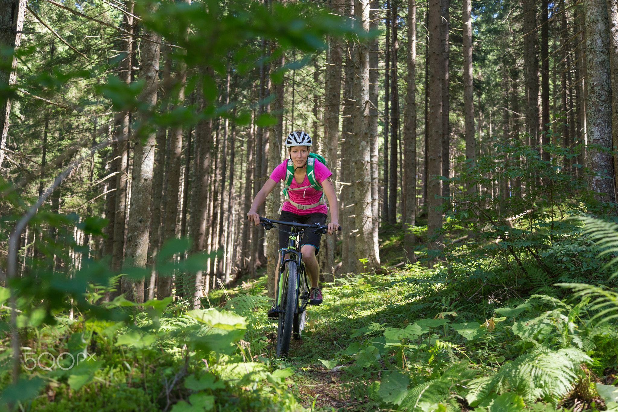 Active sporty woman riding mountain bike on forest trail .