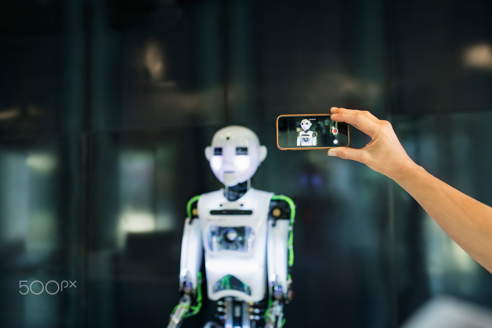 Unrecognizable scientist with smartphone and a robot.