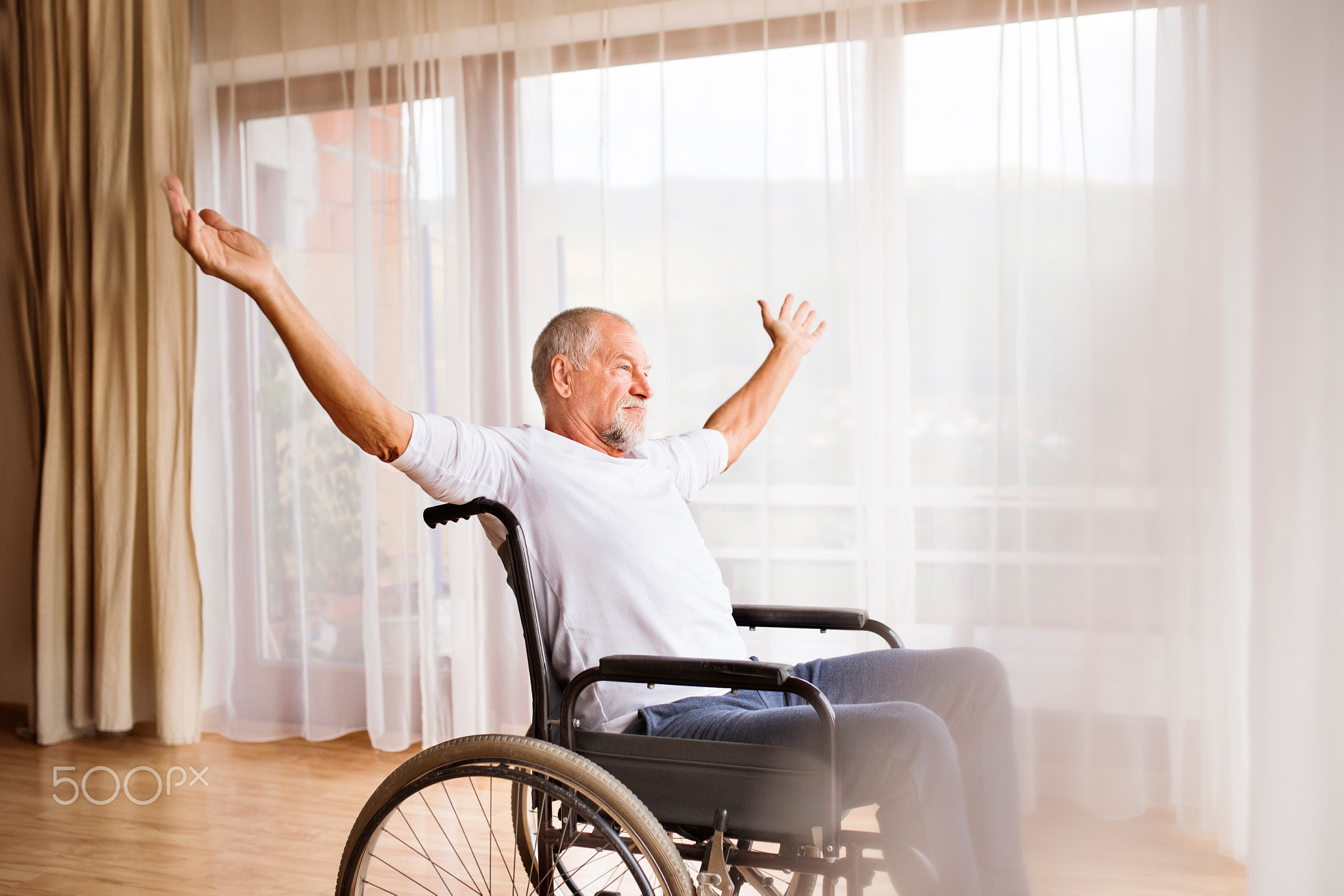 Senior man sitting on wheelchair at home.