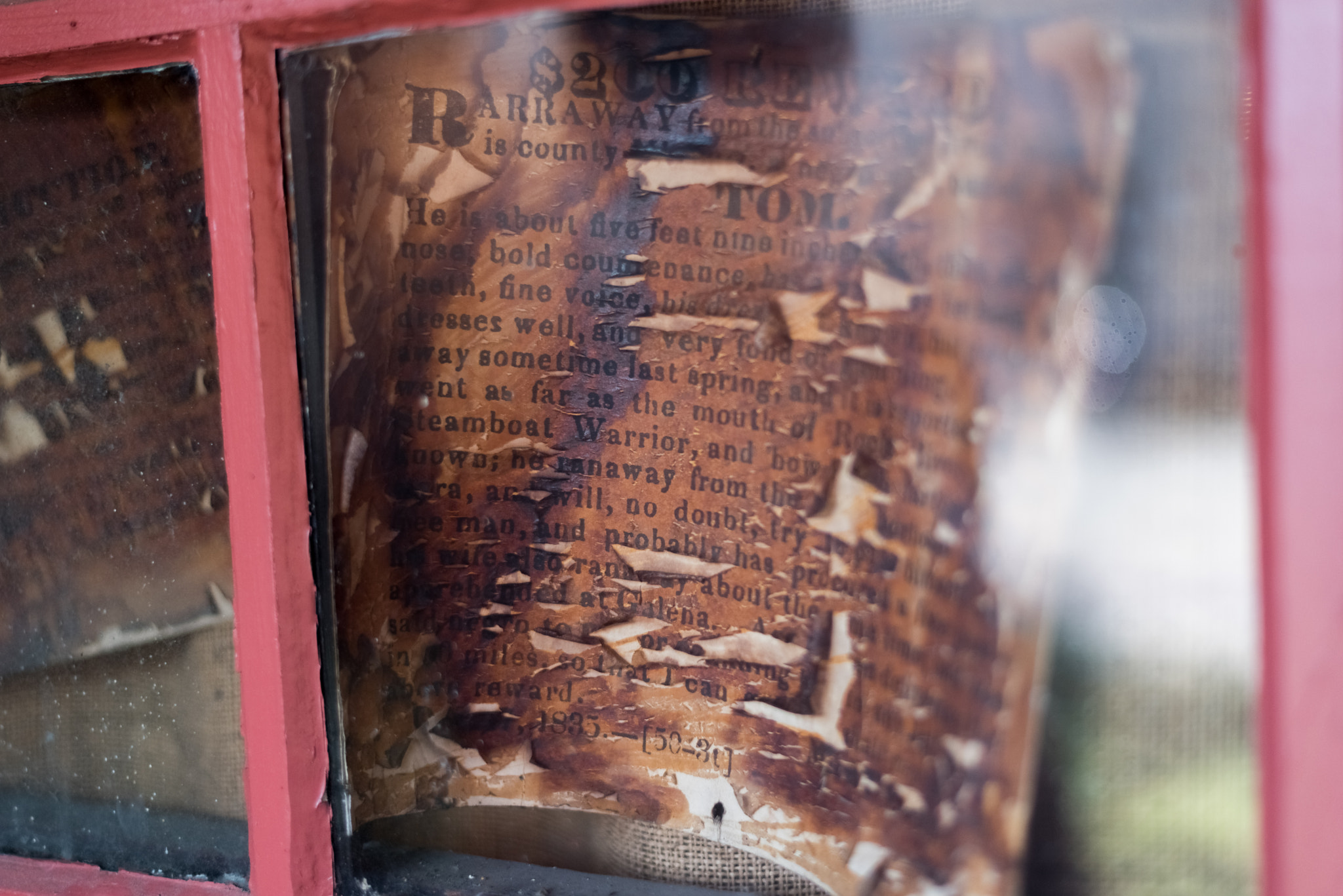 Very old died out Wanted sign behind a glass
