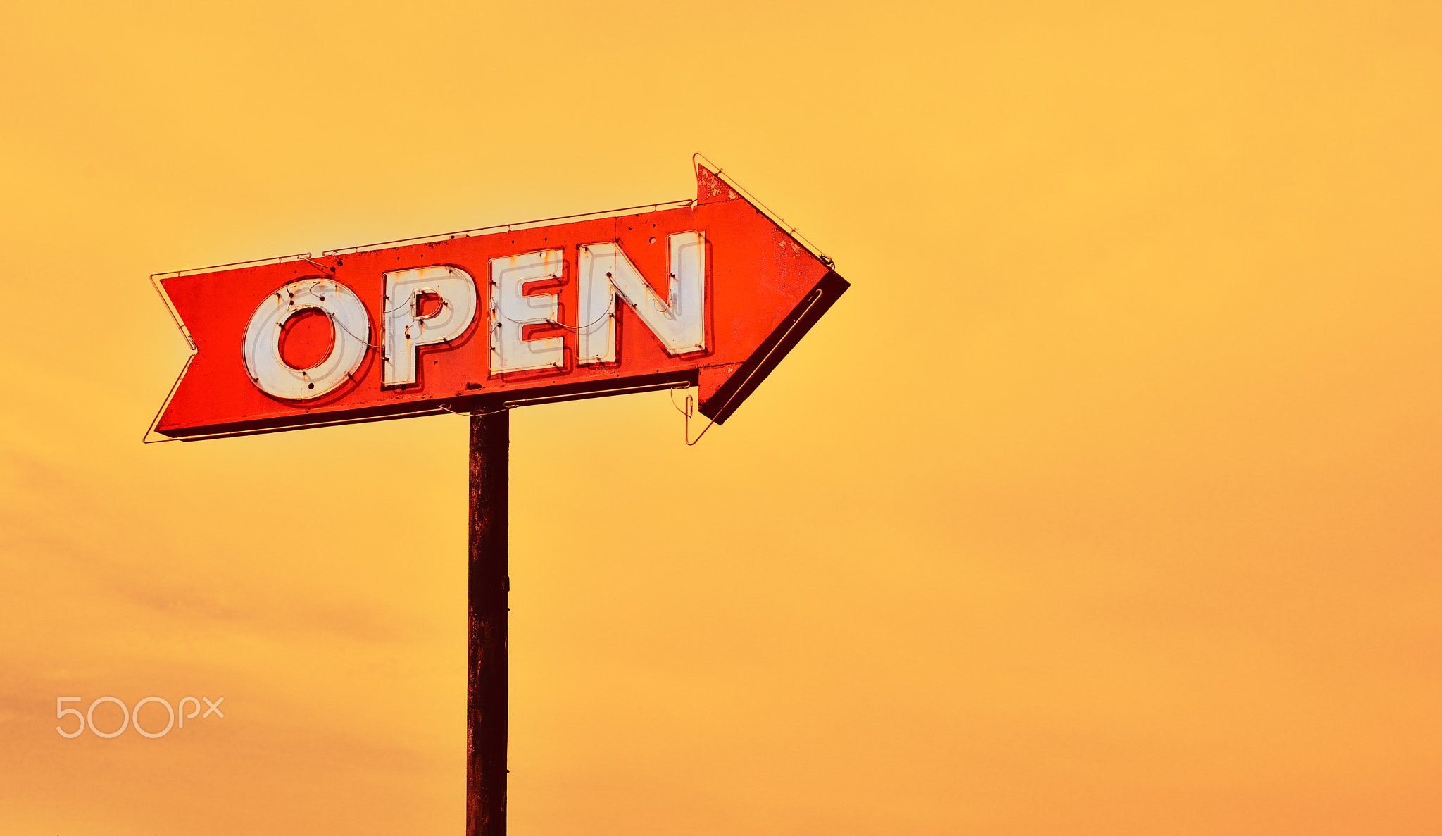 Open neon sign at sunset.