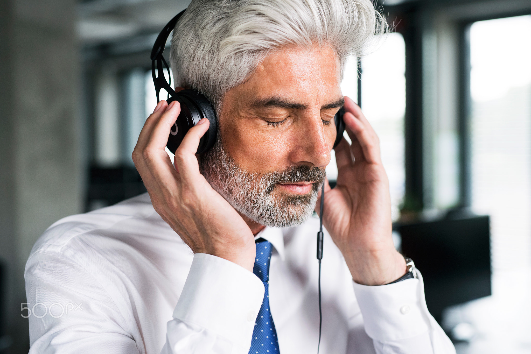 Mature businessman with headphones in the office.