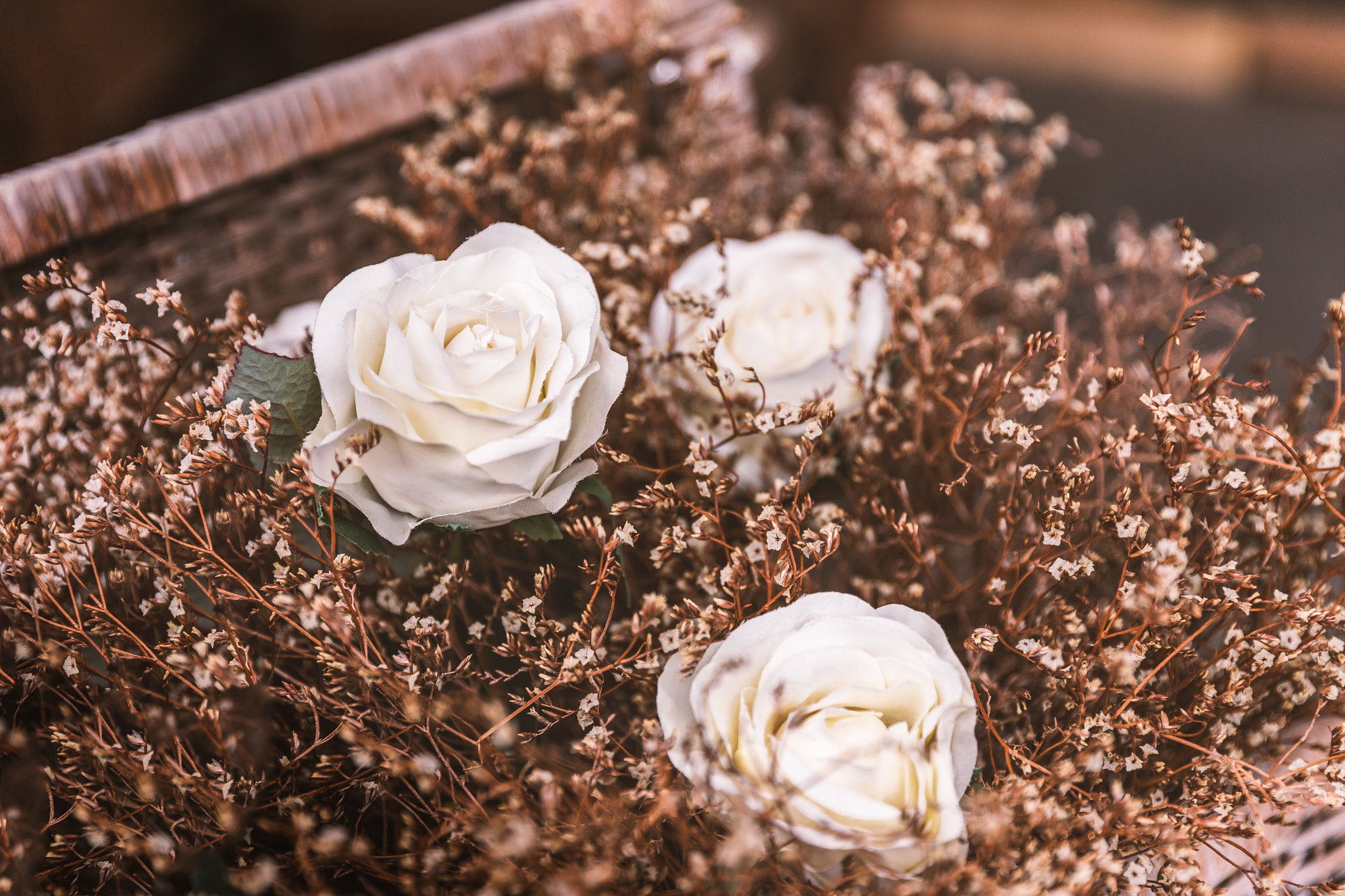 White roses with brown flower grass in basket
