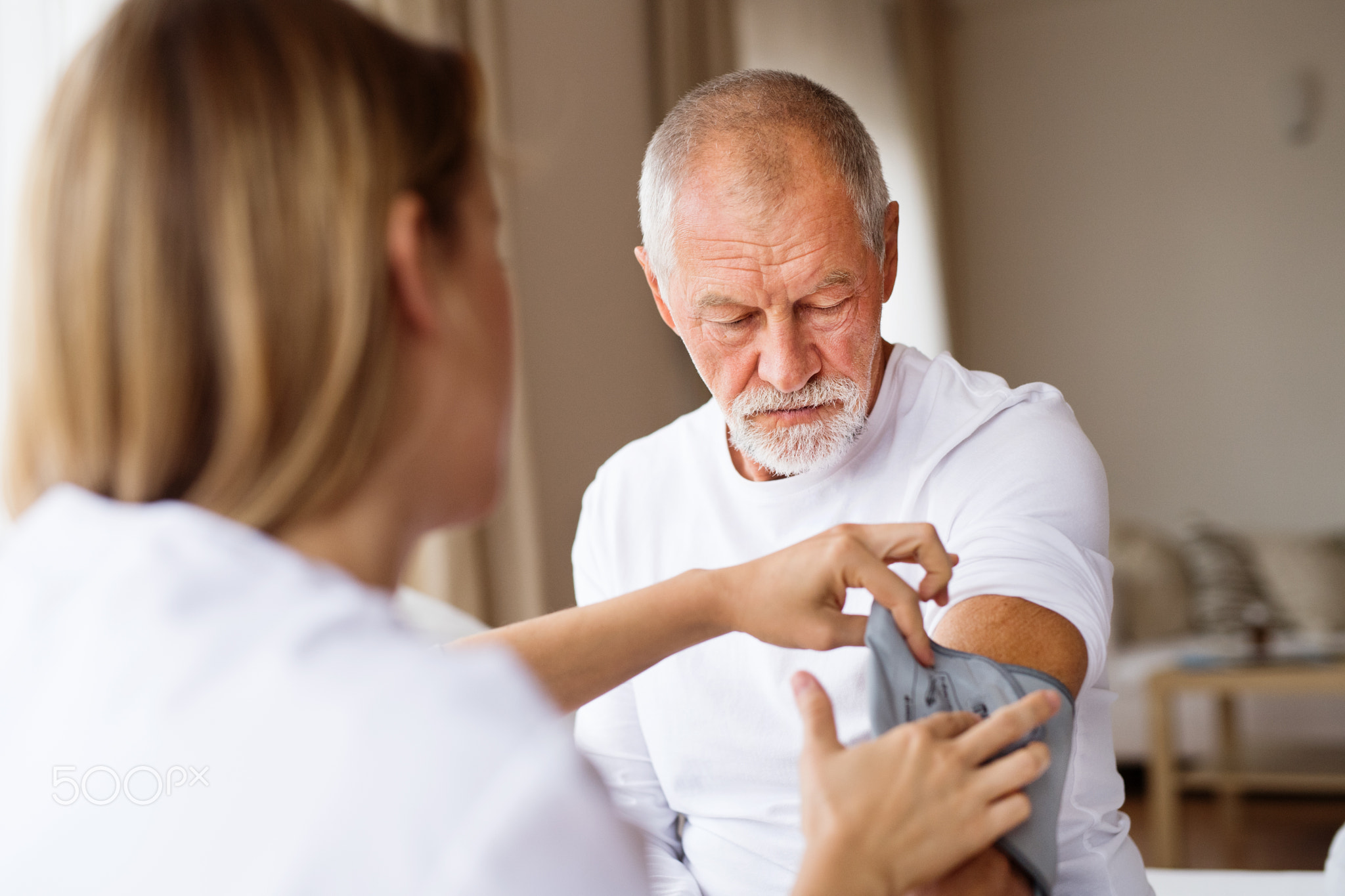 Health visitor and a senior man during home visit.