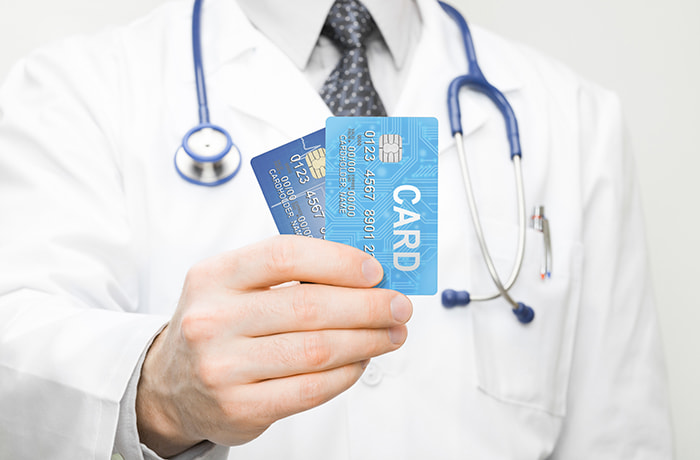 Doctor holding two credit cards in his hand - closeup studio sho