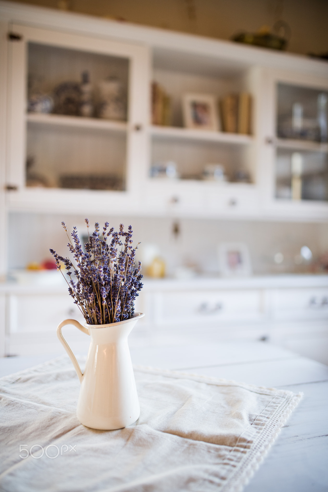 Dried lavender bunch in a white vase in vintage kitchen.