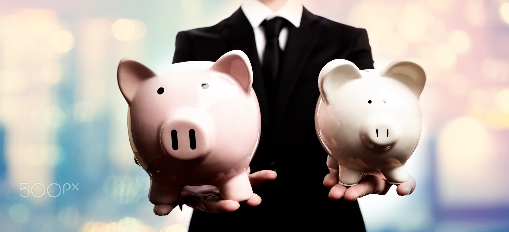 Businessman holding two piggy banks