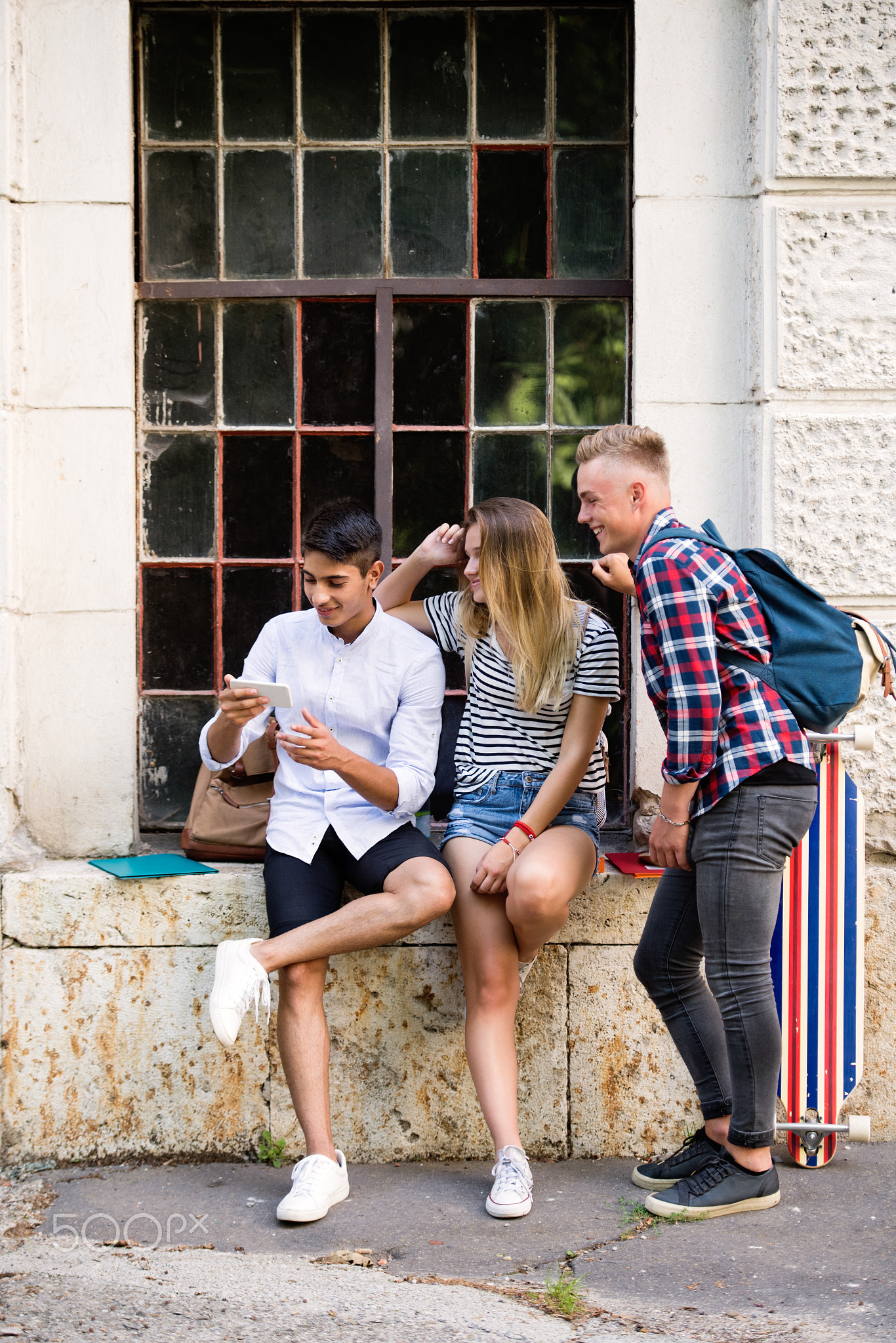 Group of students in front of university with smart phone.