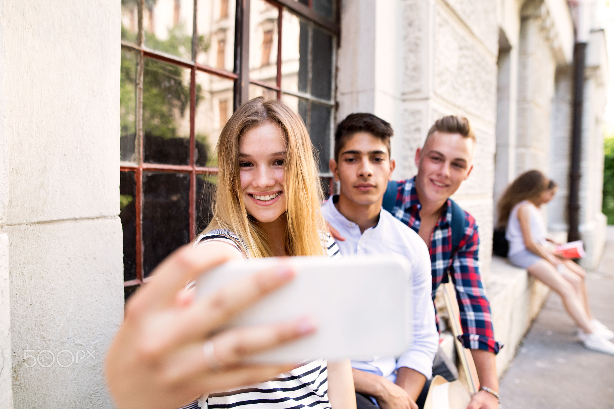 Group of students in front of university taking selfie.
