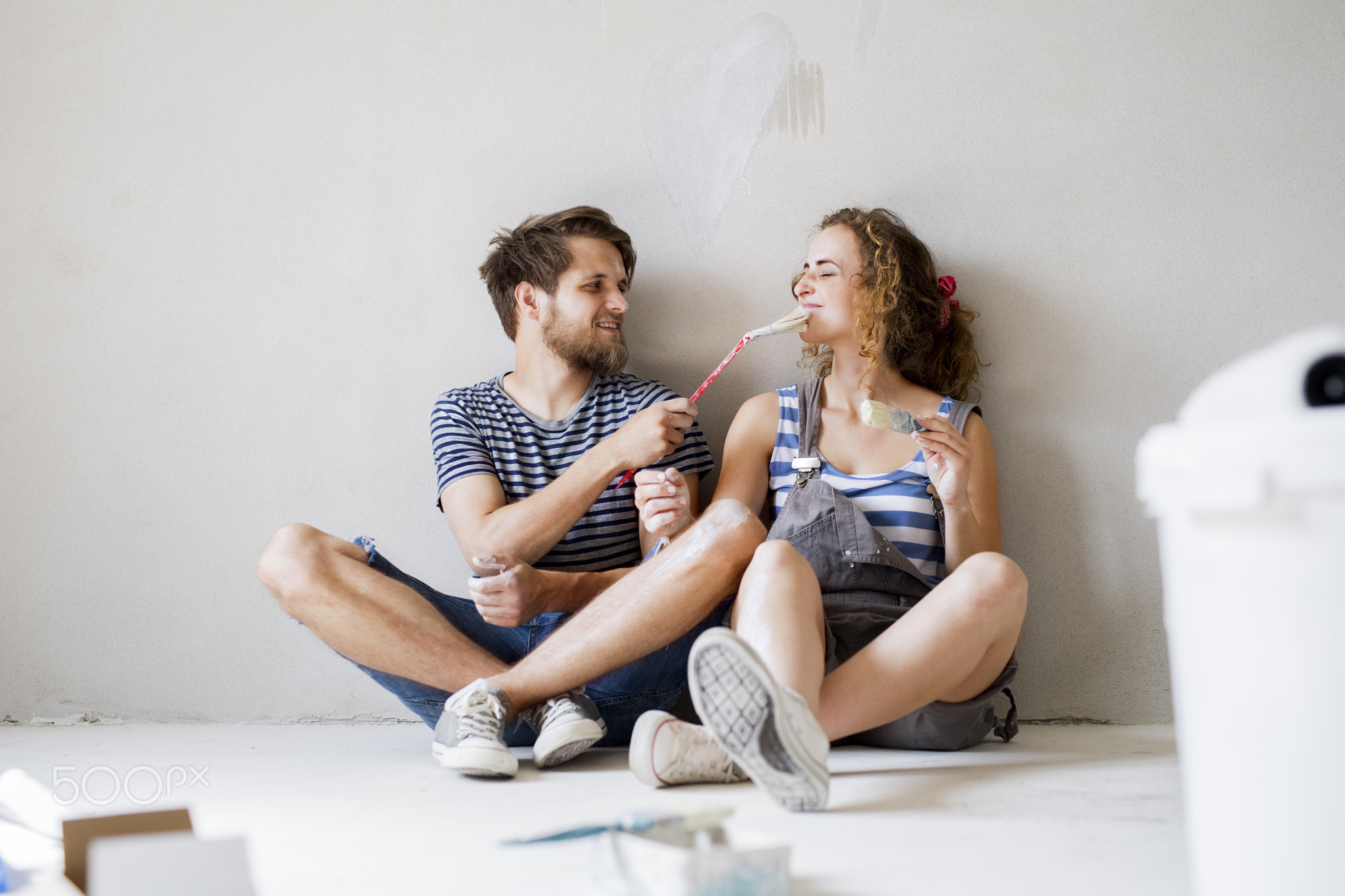 Young couple in love painting walls in their new home.