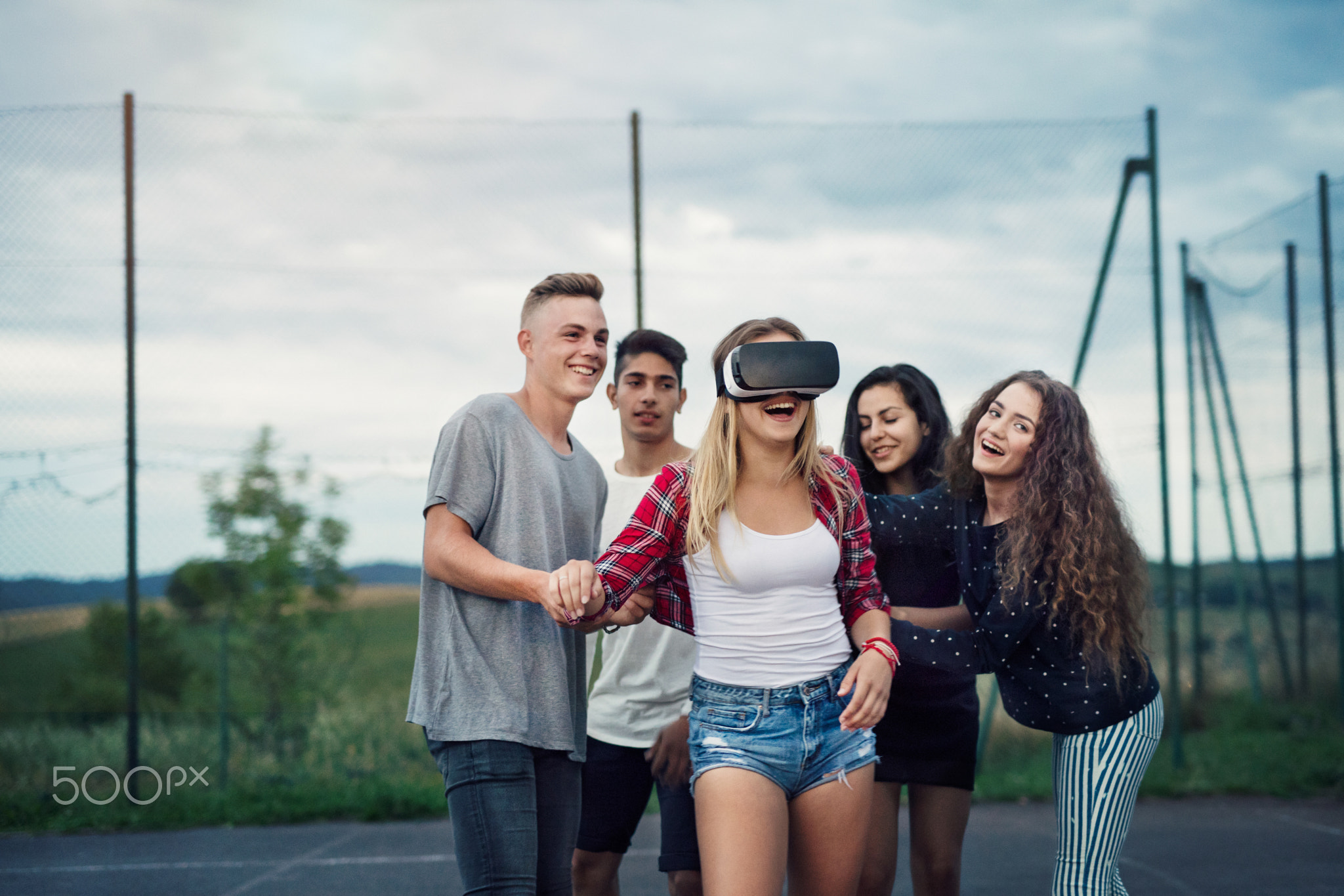 Attractive teenagers on playground. Girl with VR glasses.