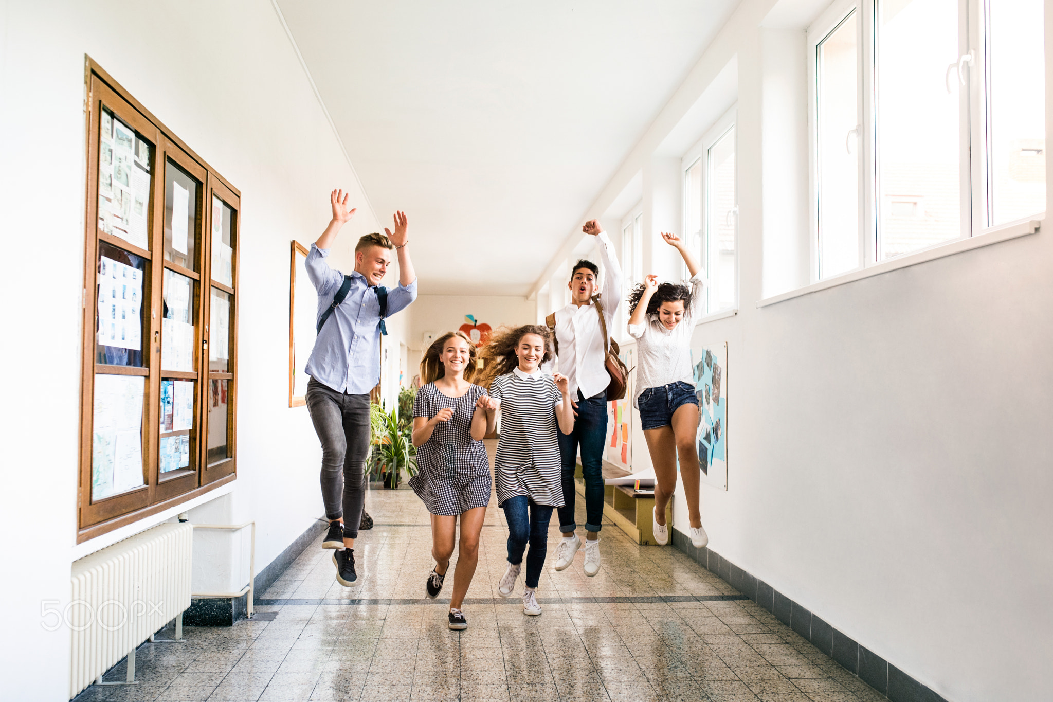 Teenage students in high school hall jumping high.