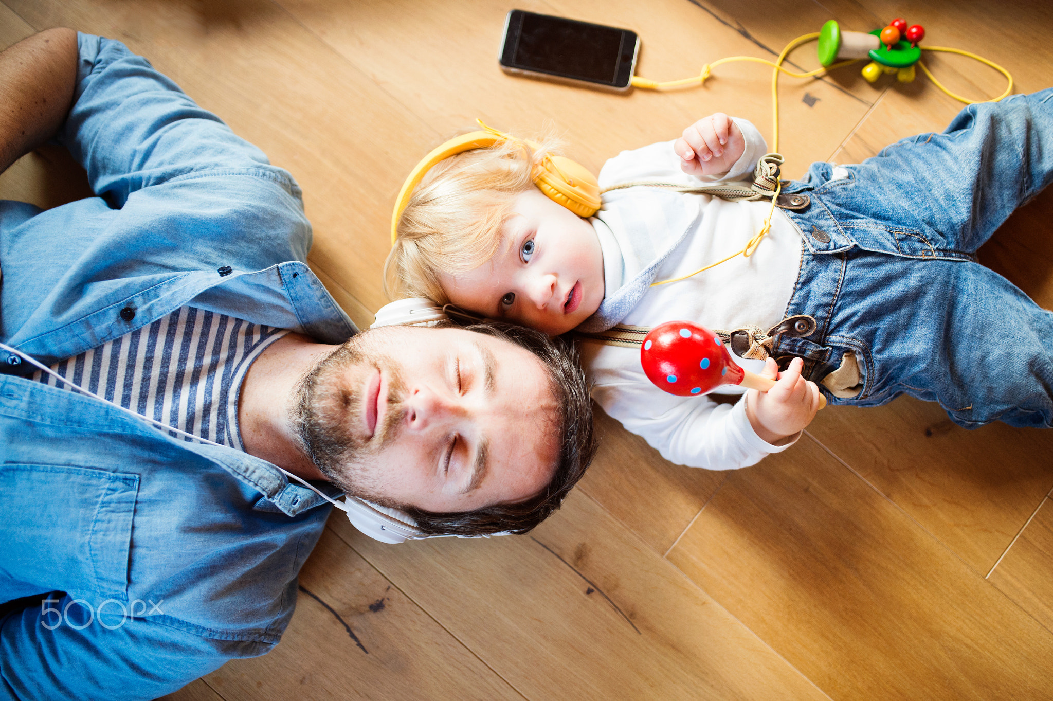 Father and son with smartphone and earphones, listening music.