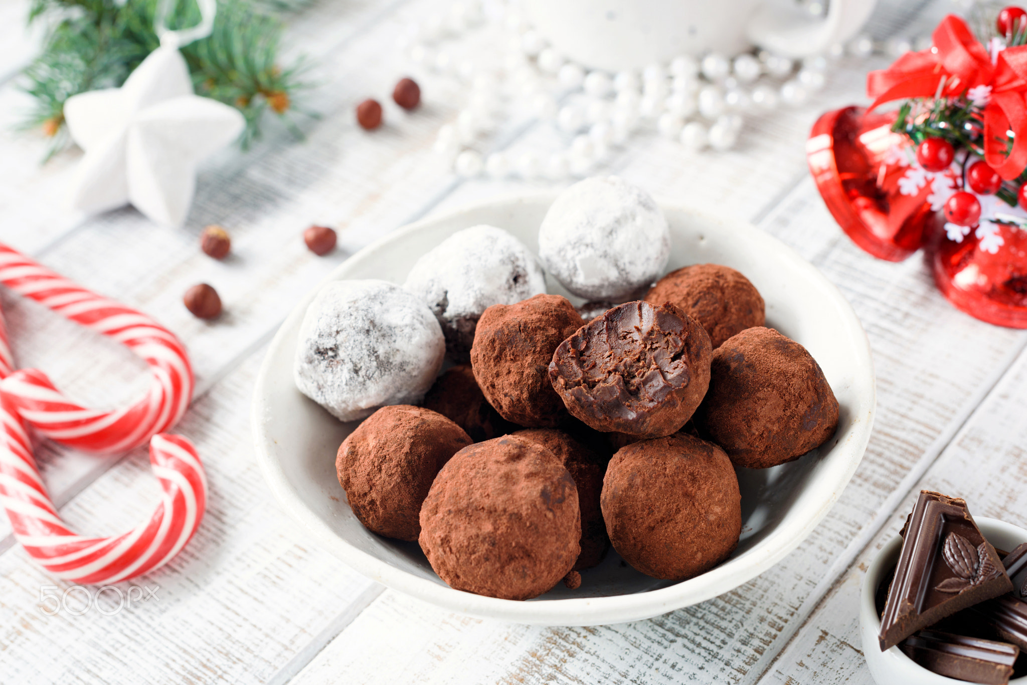 Homemade chocolate candy truffles with candy canes on white table.