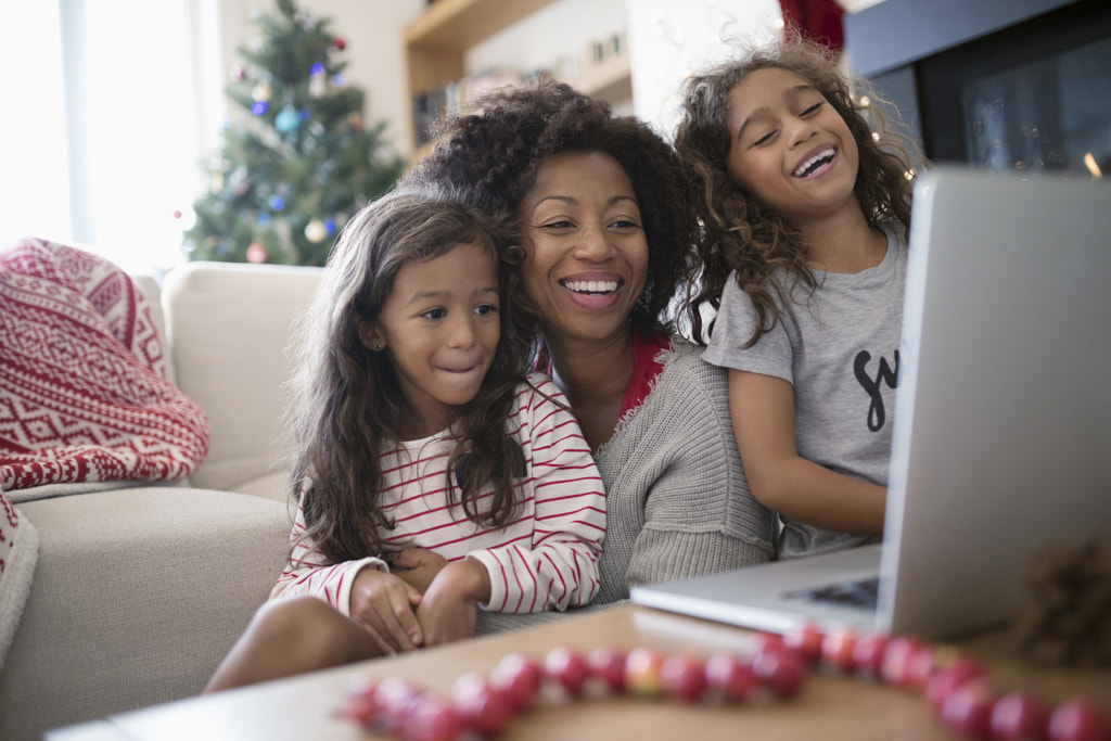 Laughing mother and daughters video chatting at laptop in Christmas living room by Hero Images Hero Images on 500px.com