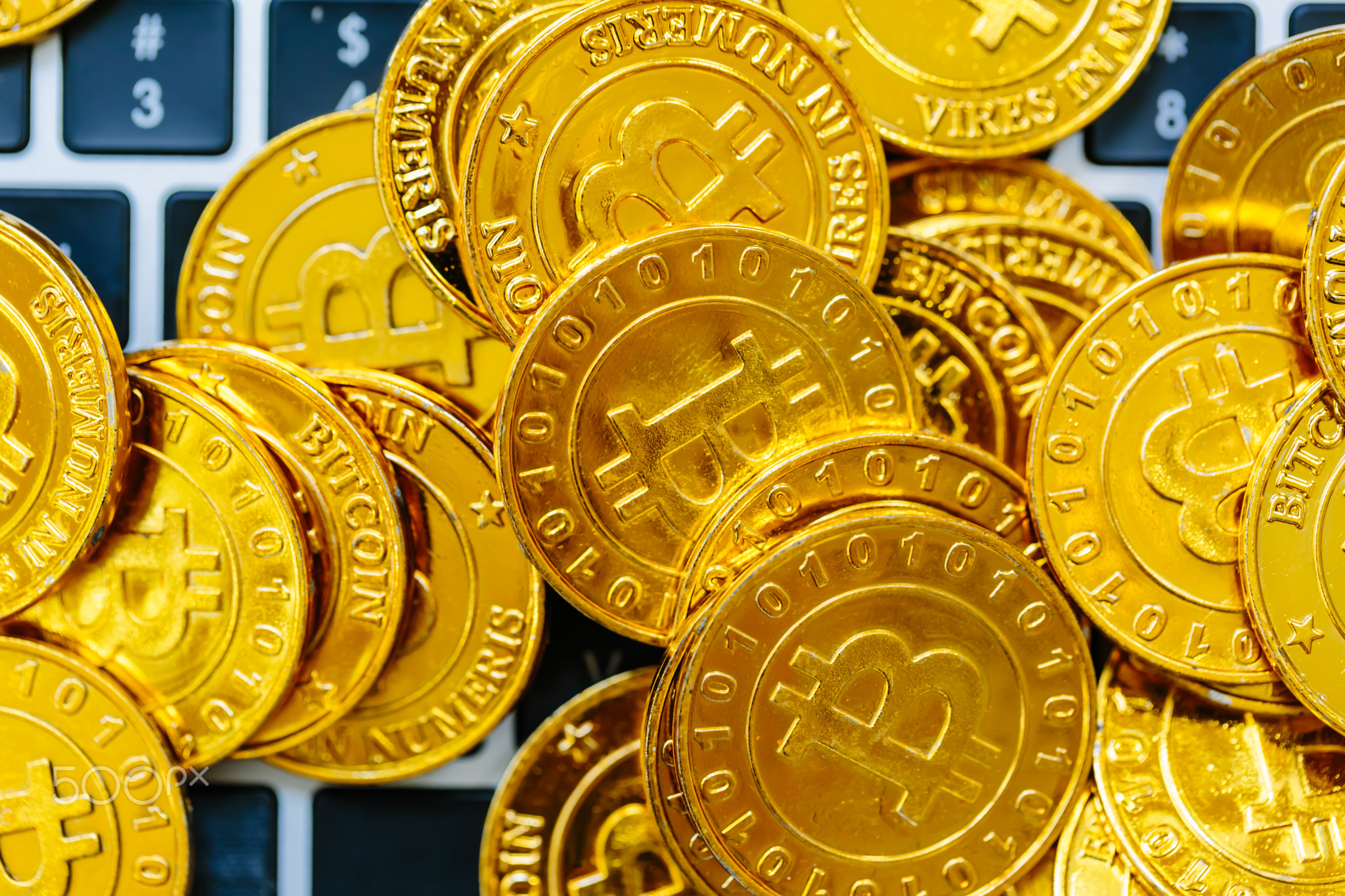 Pile of gold bitcoins on top of a laptop