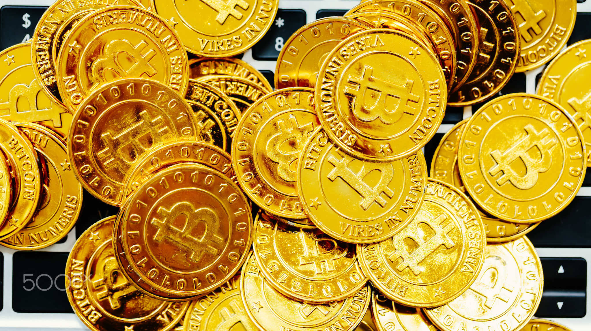 Pile of gold bitcoins on top of a laptop