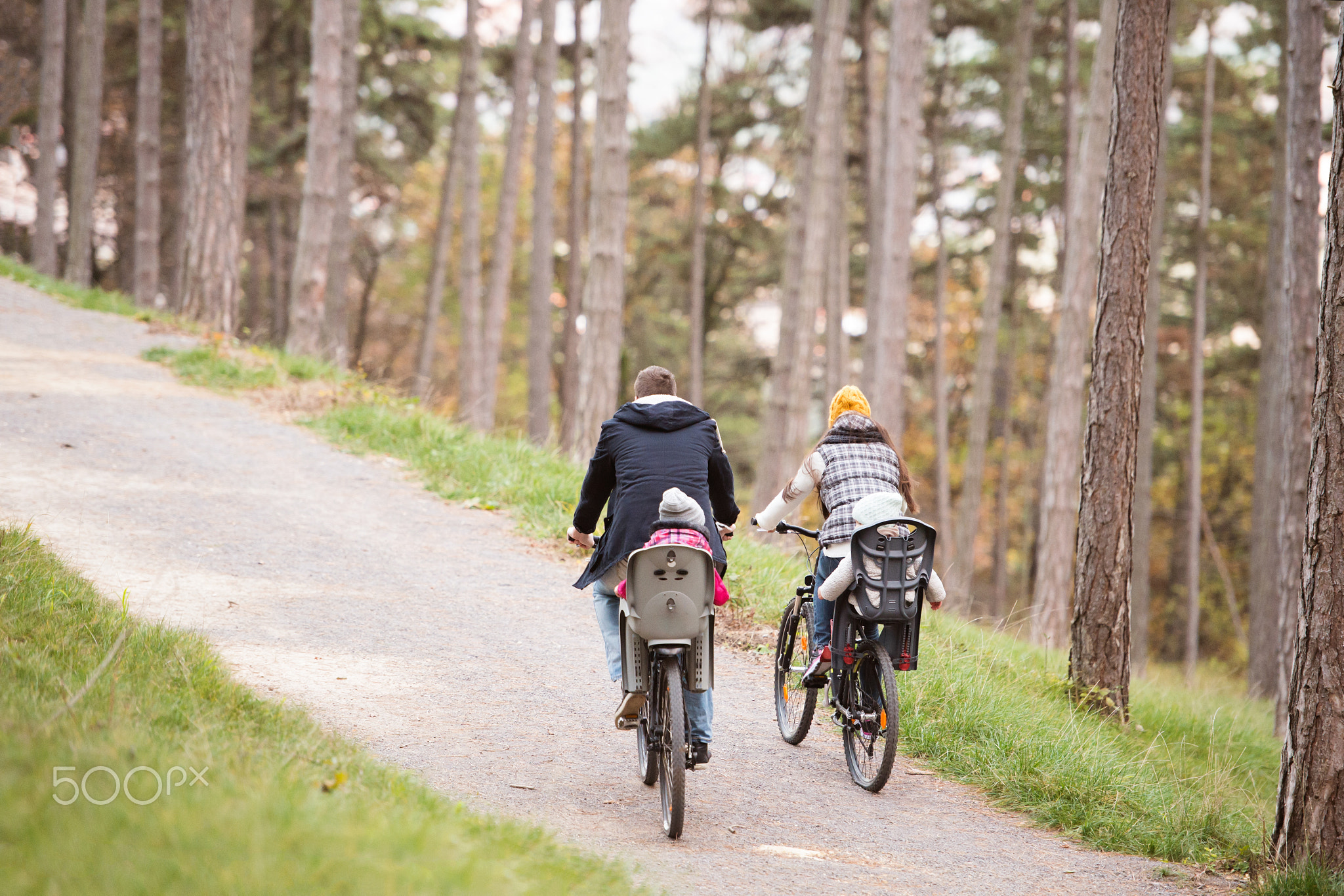 Young family in warm clothes cycling in autumn park