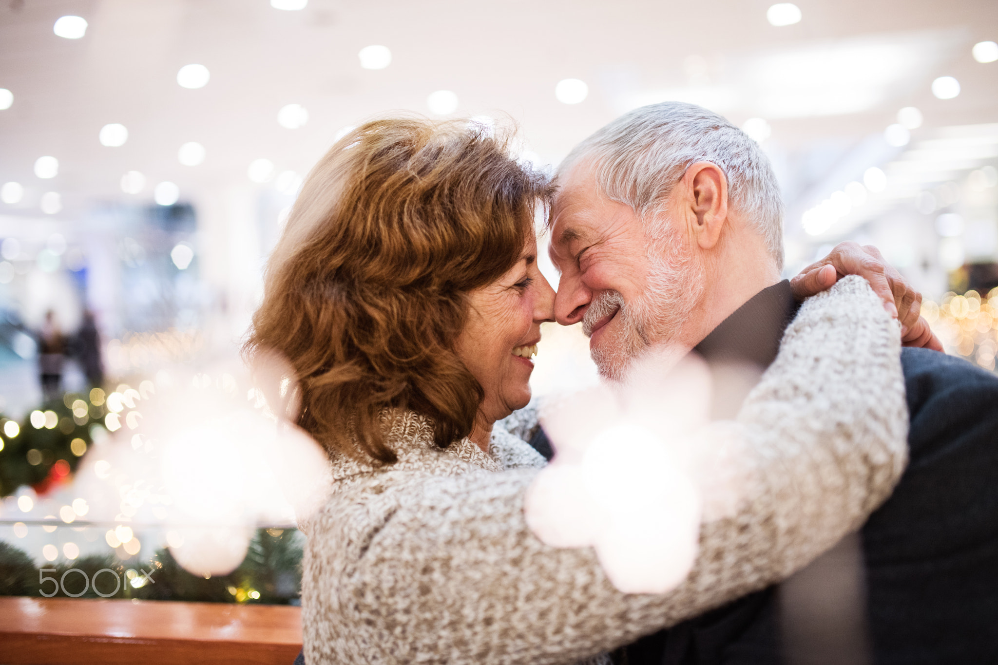 Senior couple doing Christmas shopping, hugging.