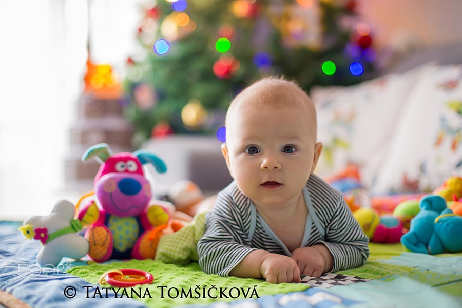 Happy three months old baby boy, playing at home on a colorful a