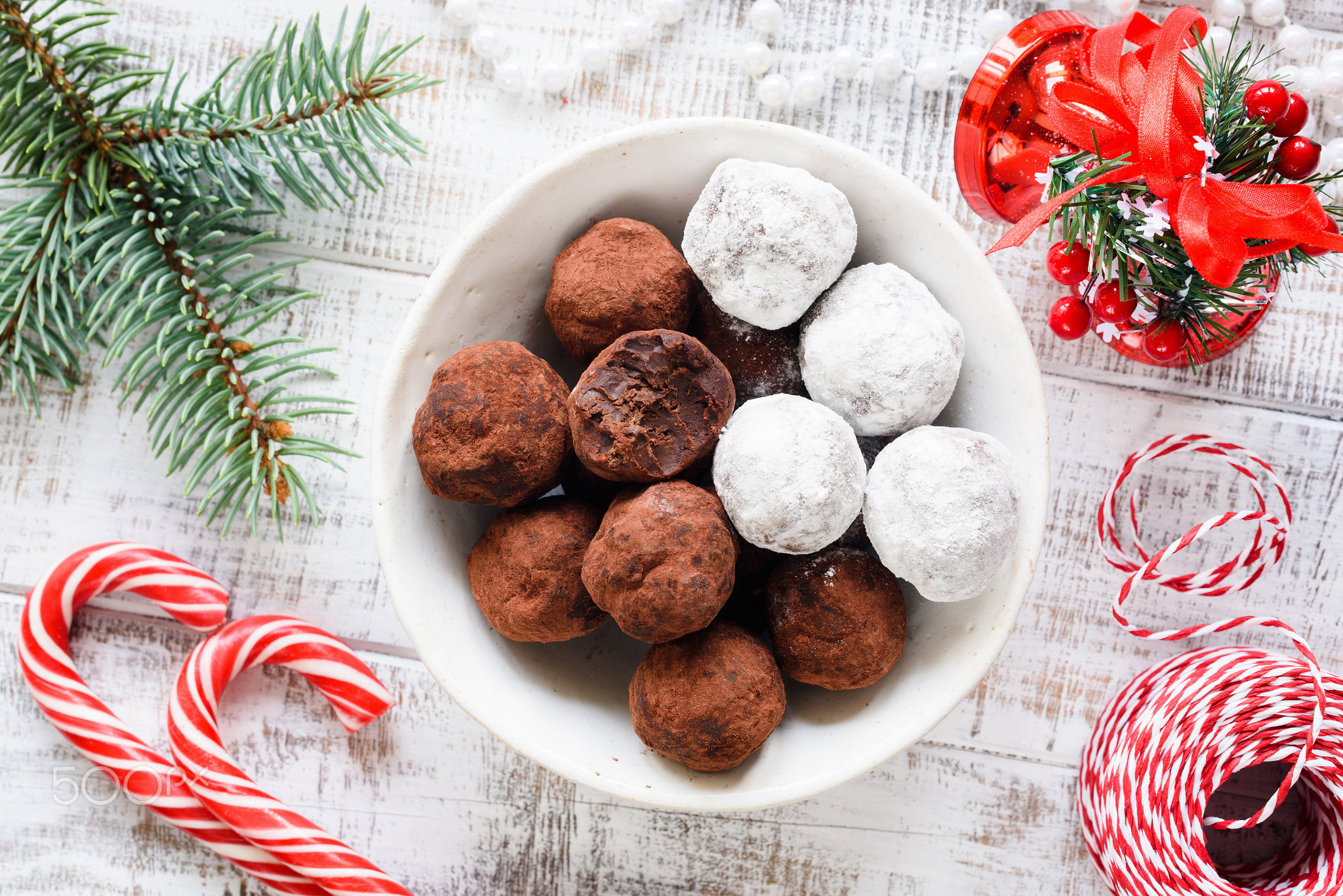 Christmas chocolate truffles, candy canes and fir tree branch on old white table