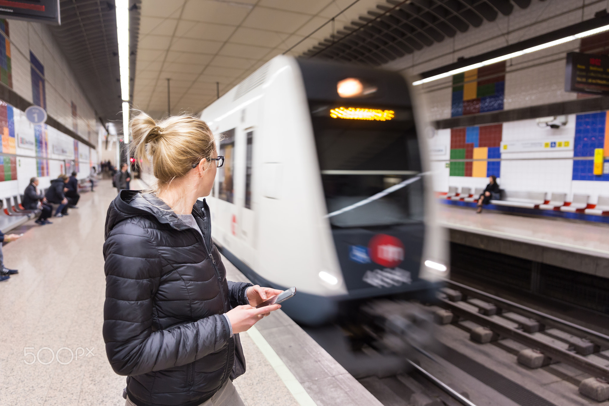 Woman with a cell phone waiting for metro.
