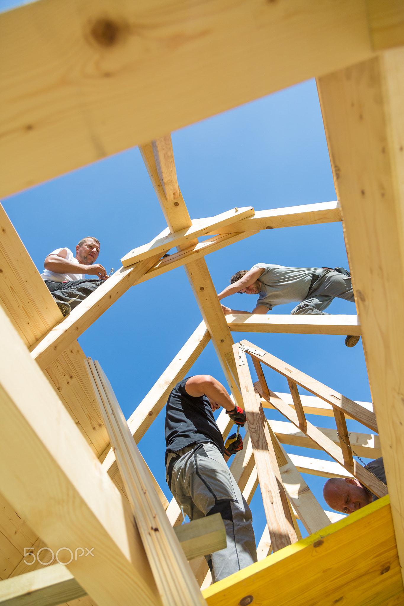 Builders at work with wooden roof construction.