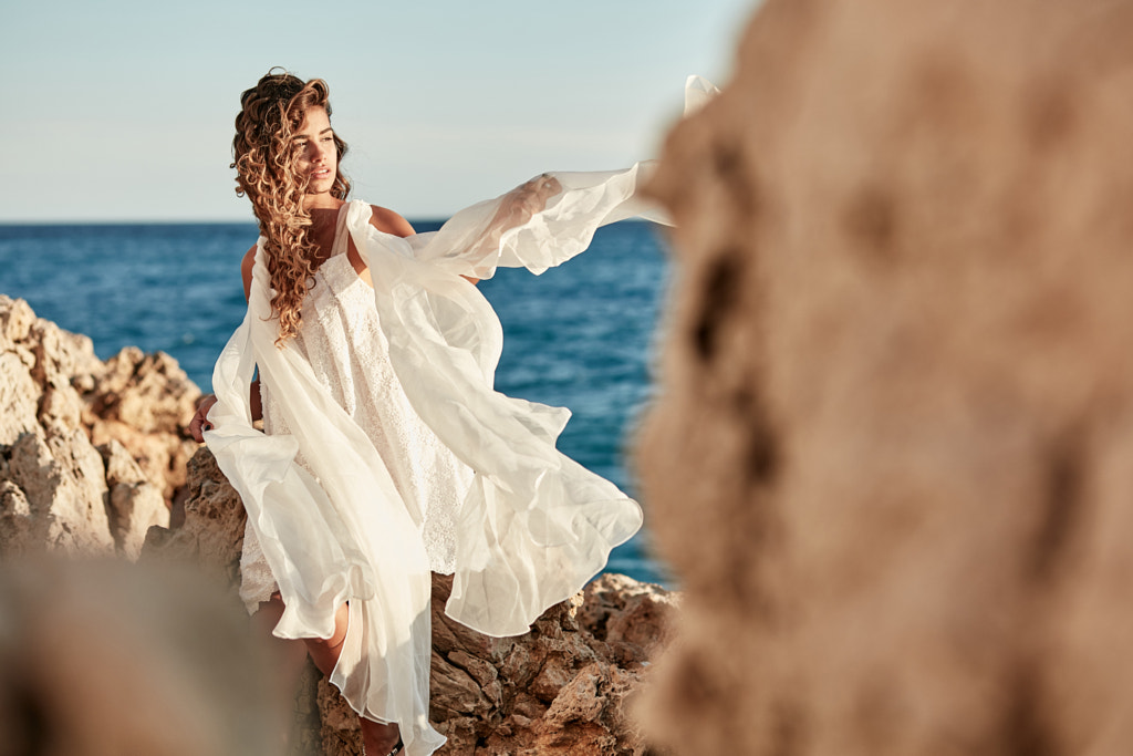 Portrait of beautiful sexy young woman model with long dark hair wearing long white dress posing... by Jaroslav Monchak on 500px.com