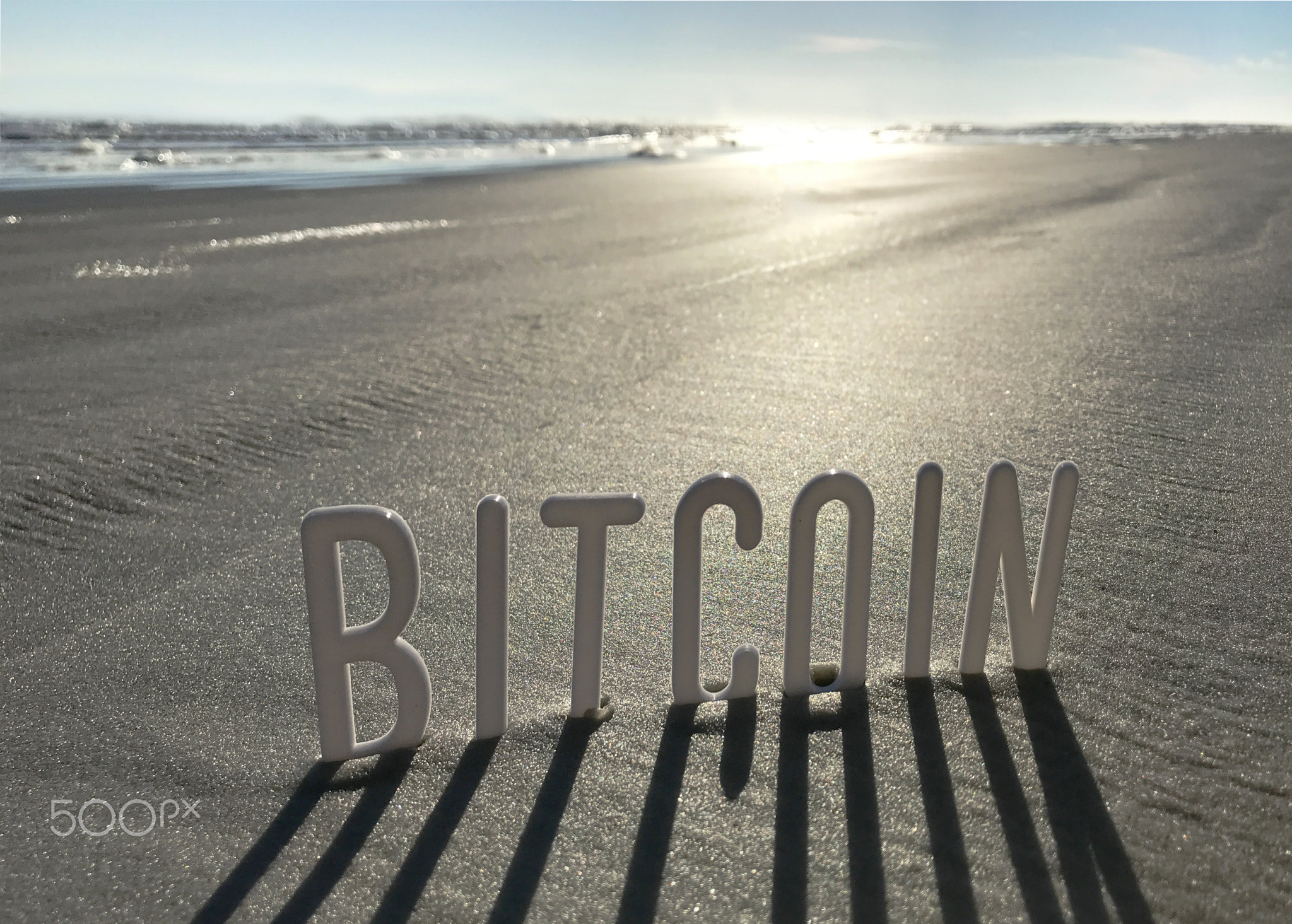 Bitcoin word in Sand with Shadows by Sun