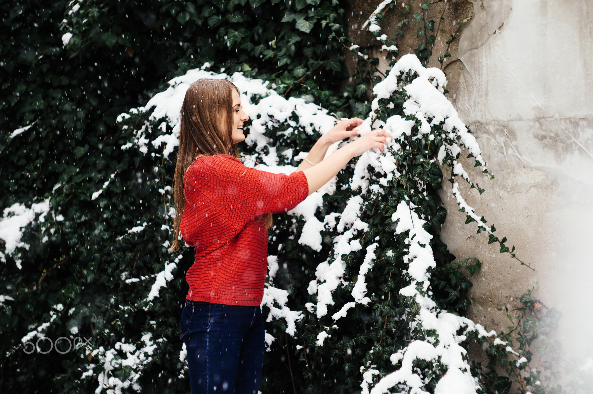 Beautiful young girl model in winter in a parked park. in a red sweater.