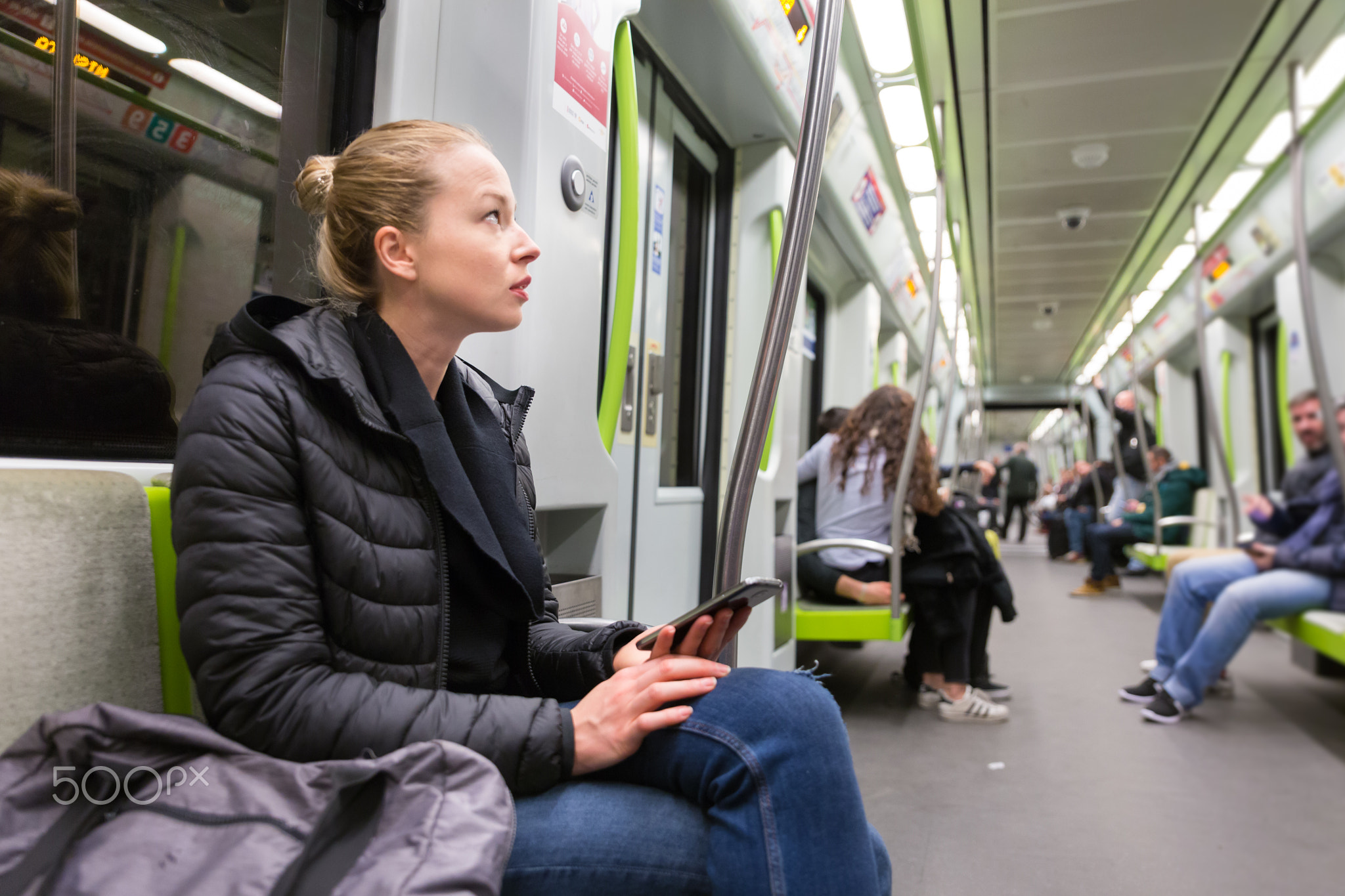 Young girl with mobile phone traveling on metro.