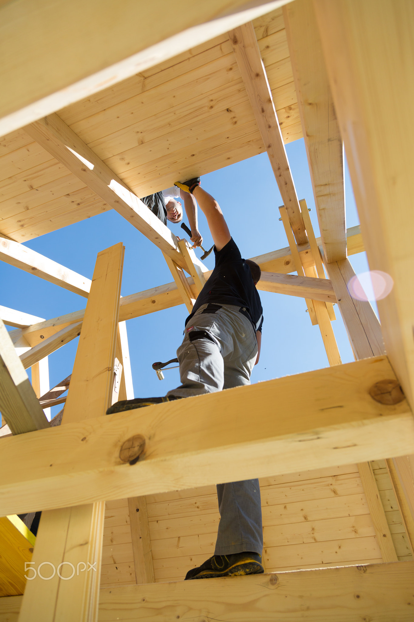 Builders at work with wooden roof construction.