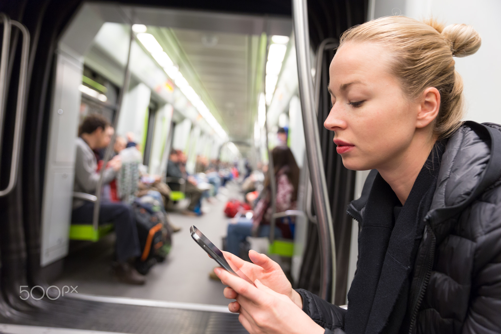 Young girl reading from mobile phone screen in metro.