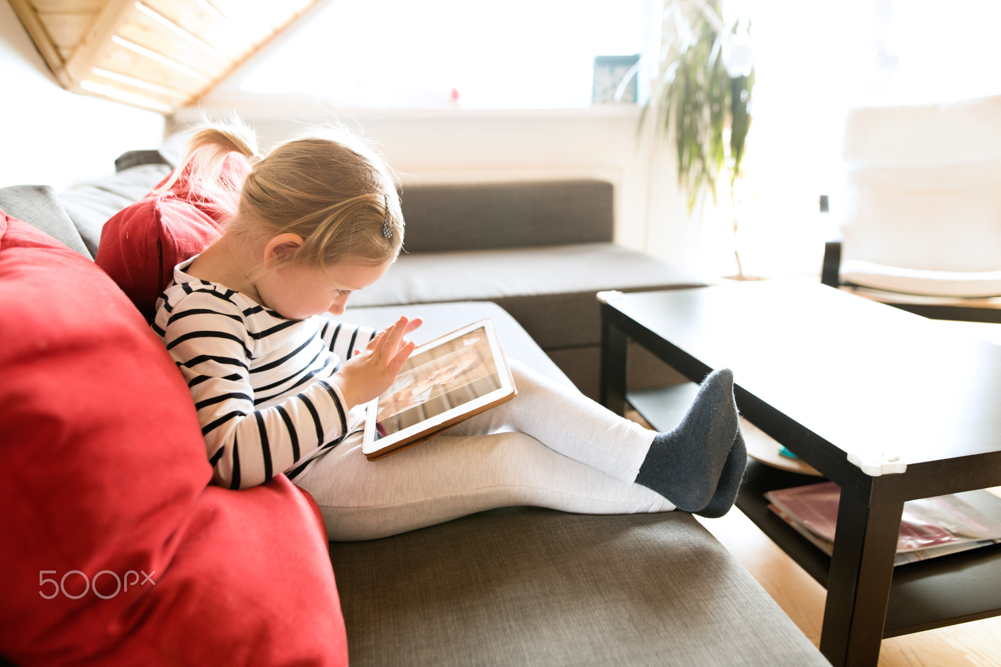 Little girl at home with tablet, video chatting with her mother.