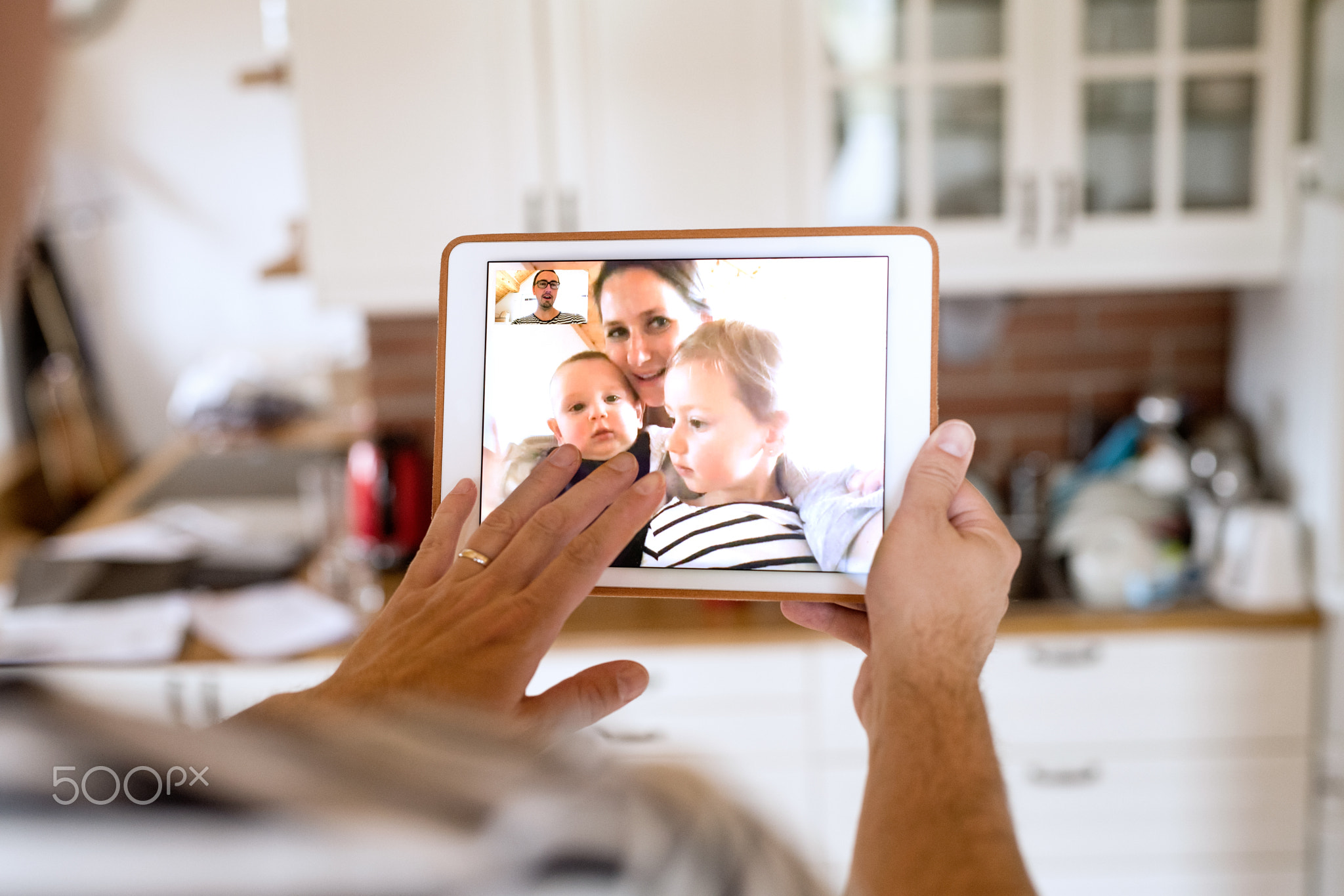 Father at home with tablet, video chatting with his family.