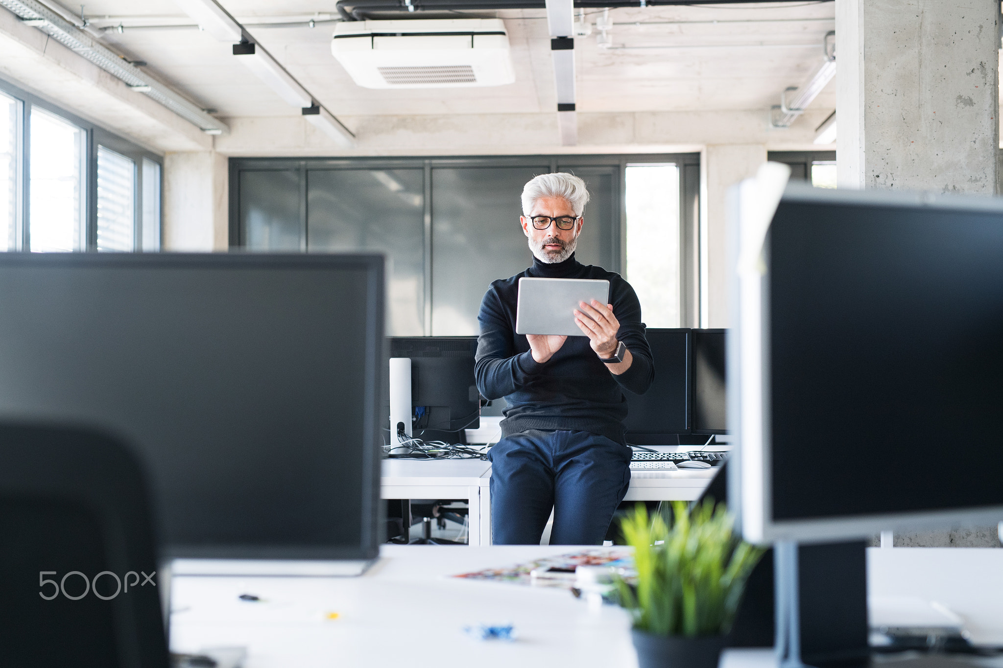 Mature businessman with tablet in the office.