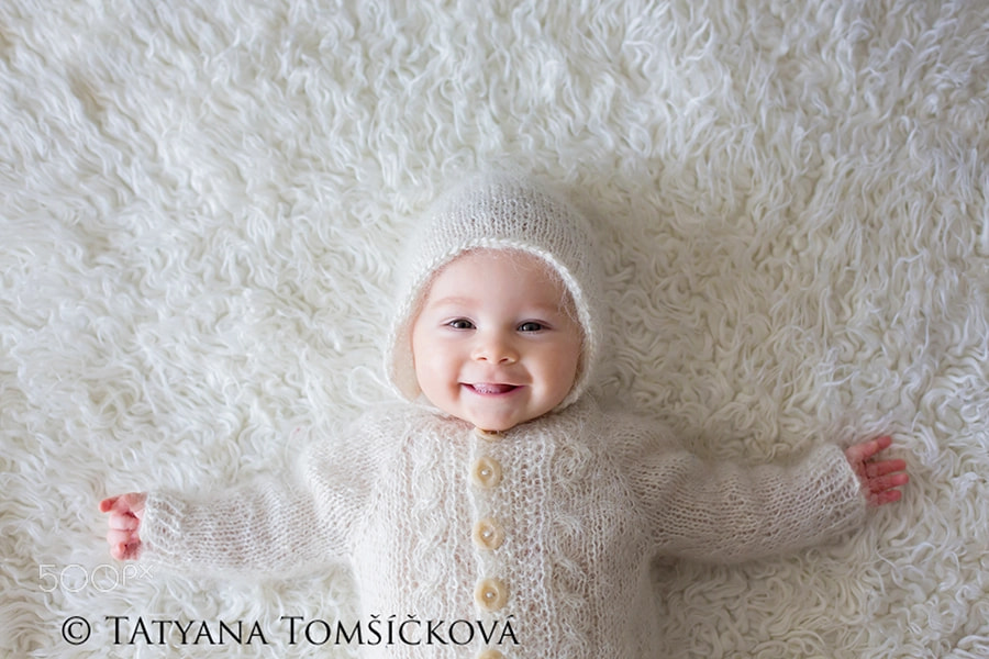 Close portrait of a little baby boy in white knitted onesie and