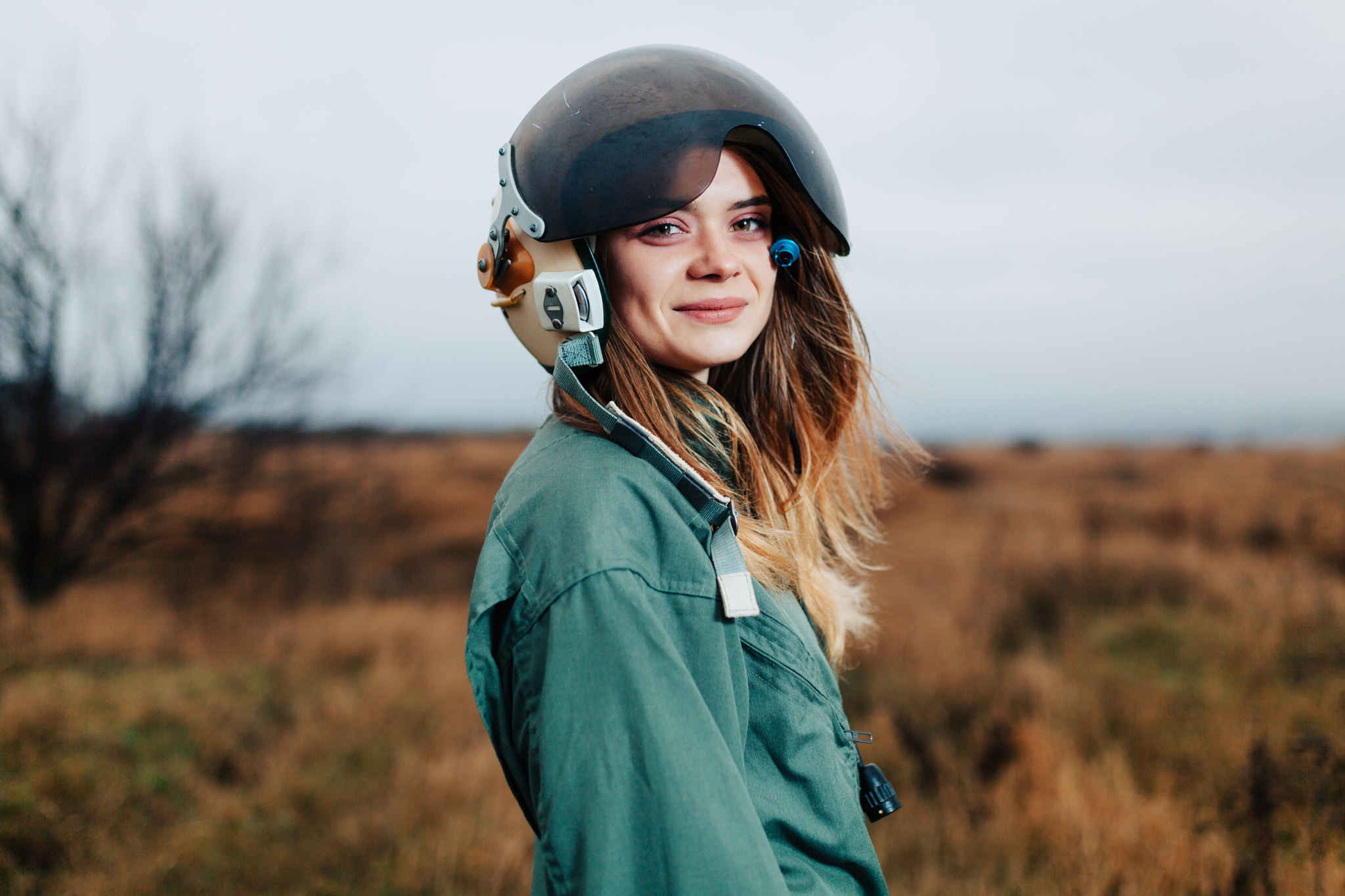 beautiful woman pilot of plane standing in the sunset field